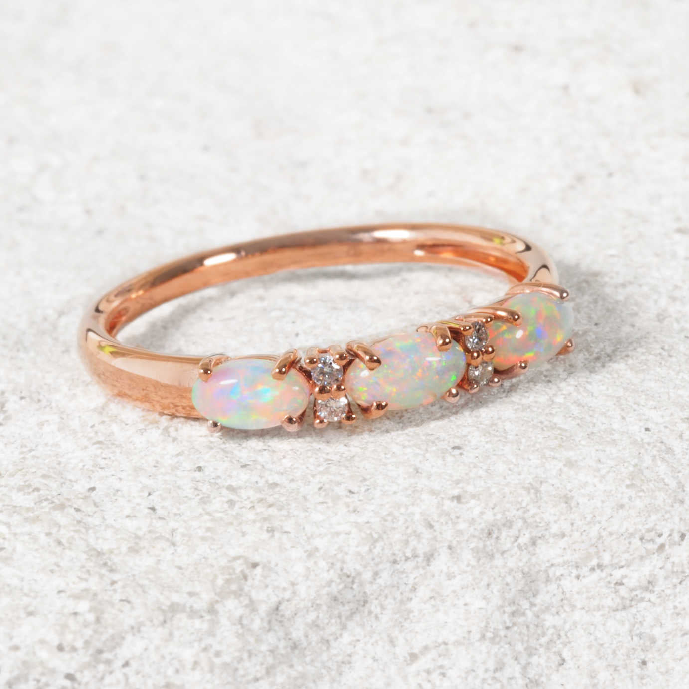 Australian white opal Rose gold ring with opal stones on a light gray background