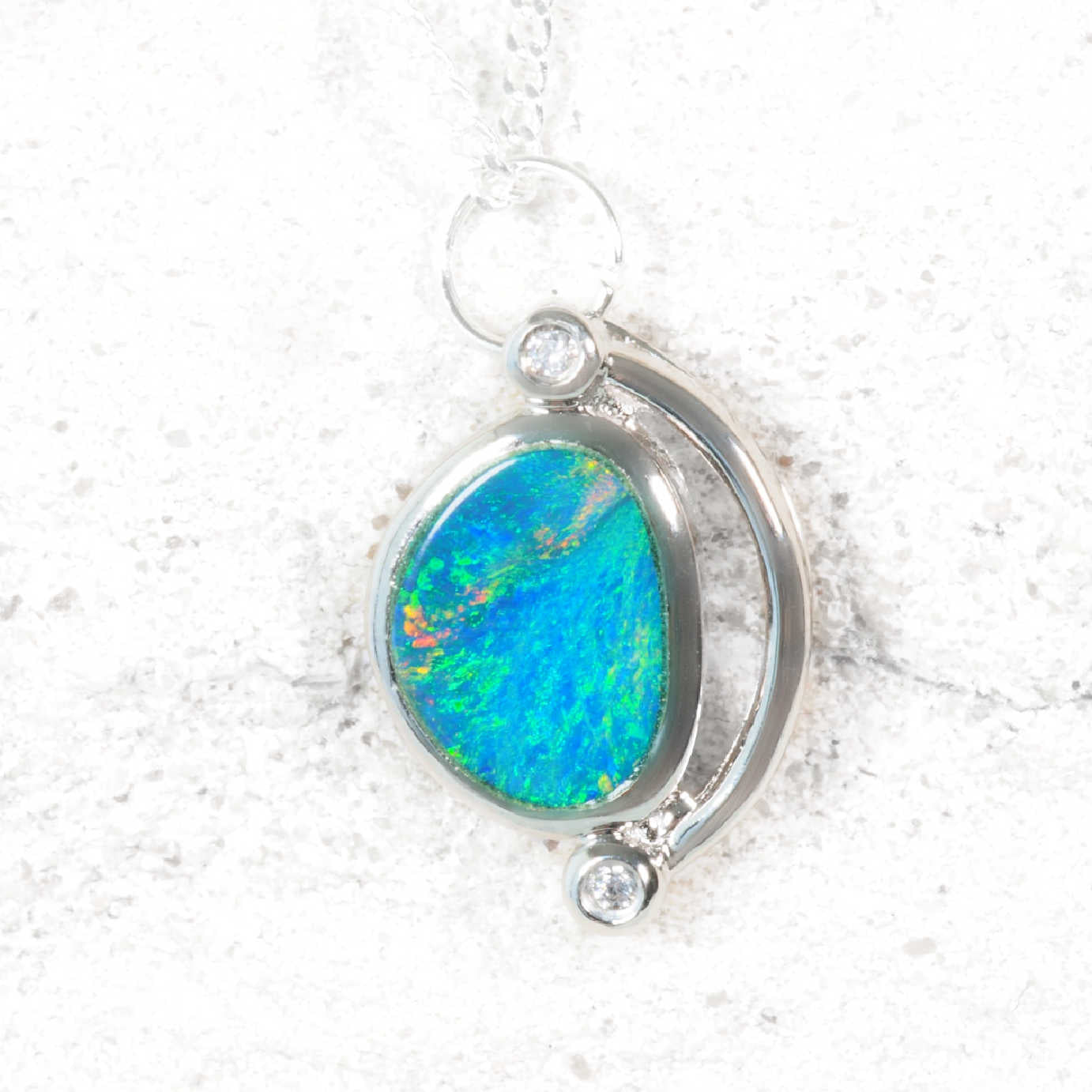 Opal pendant with silver setting on a textured white background