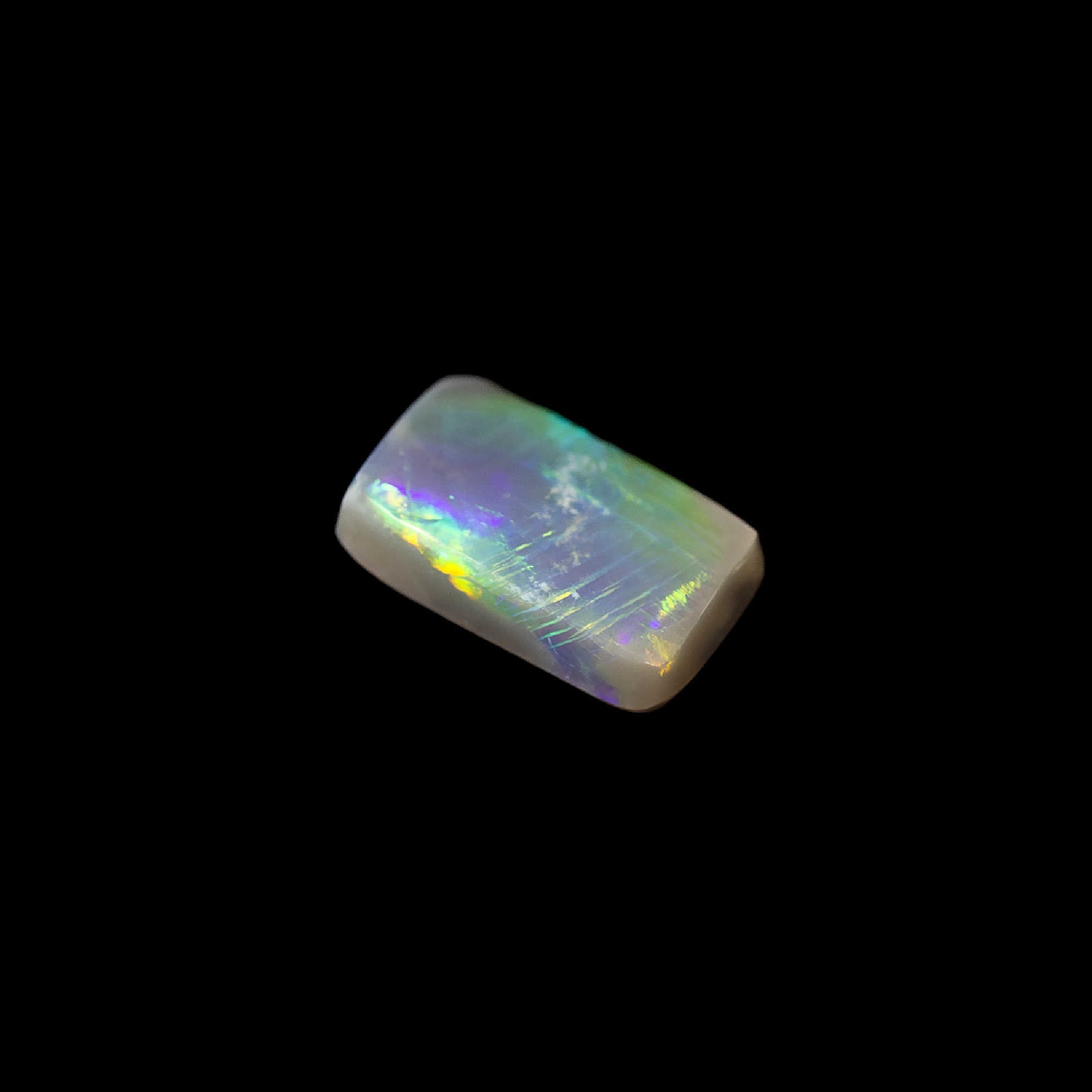 Australian semi-black opal in rectangular cut with bright green pinfire pattern