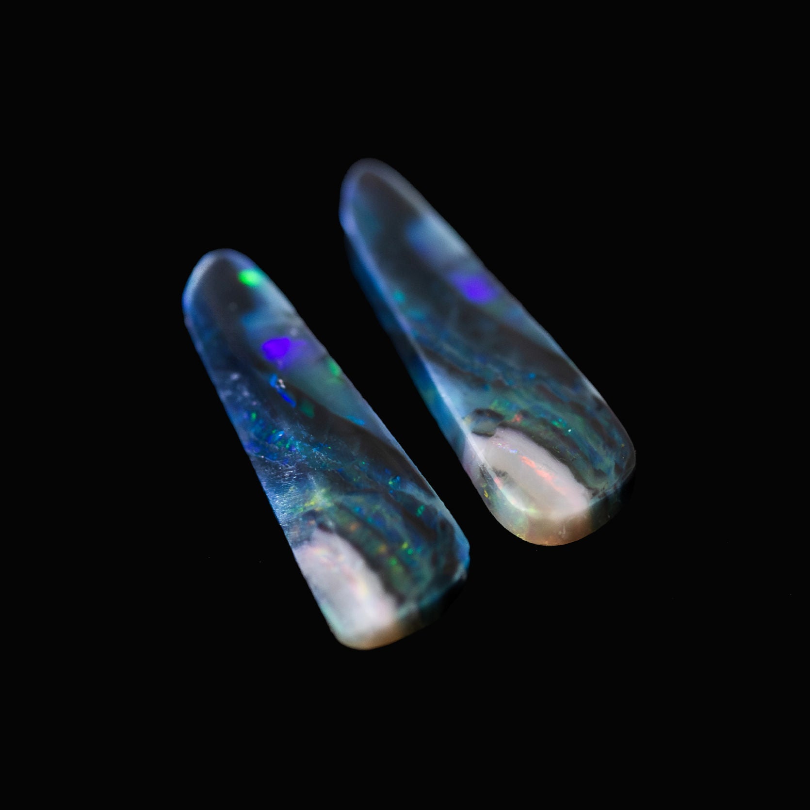 Two Australian opal gemstones with colorful internal patterns on a black background