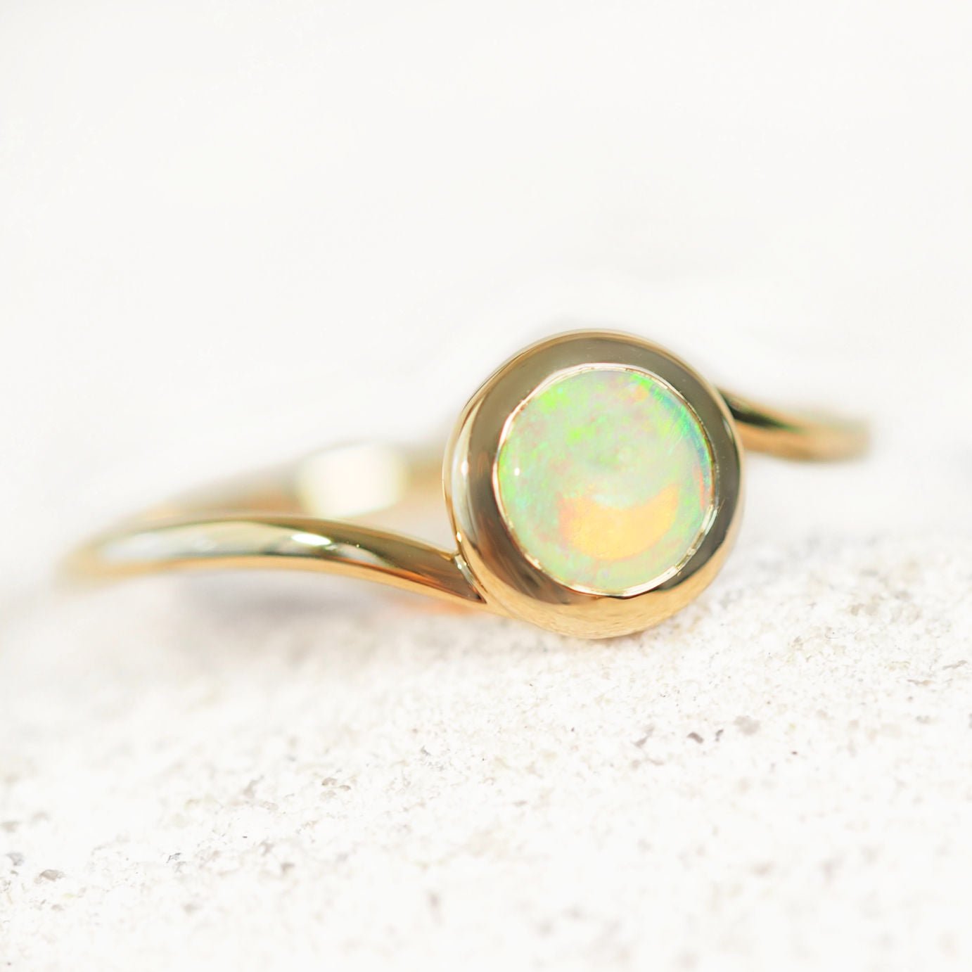 Gold Australian opal ring with a green opal stone on a white background