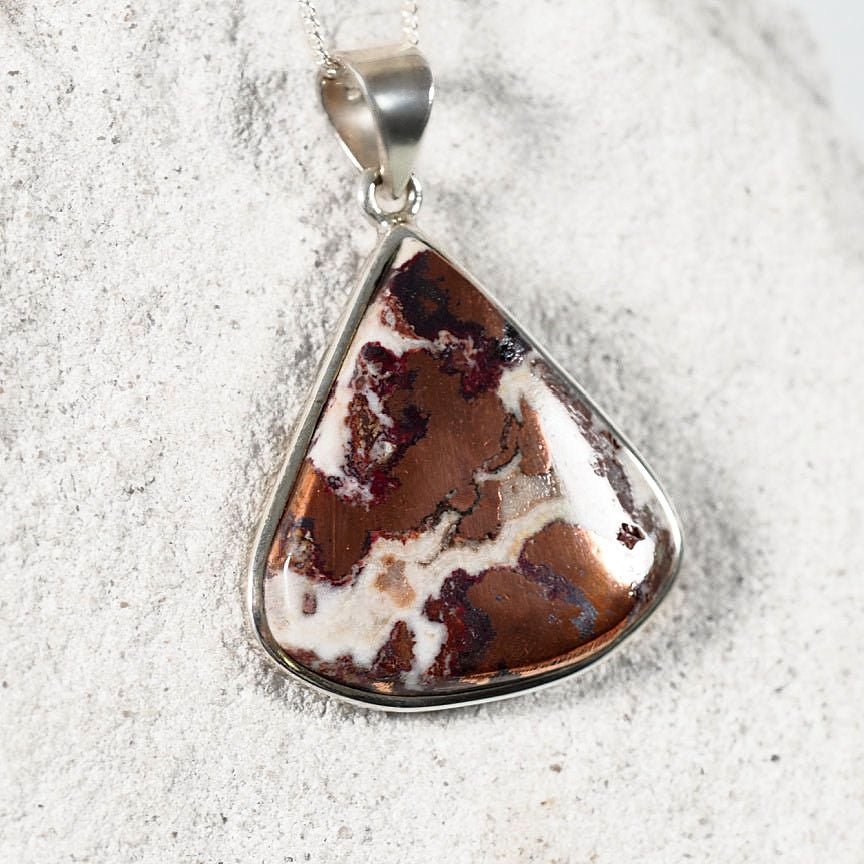 Teardrop-shaped Copper Dolomite pendant in silver, displaying unique earthy tones of copper, red, brown, and white