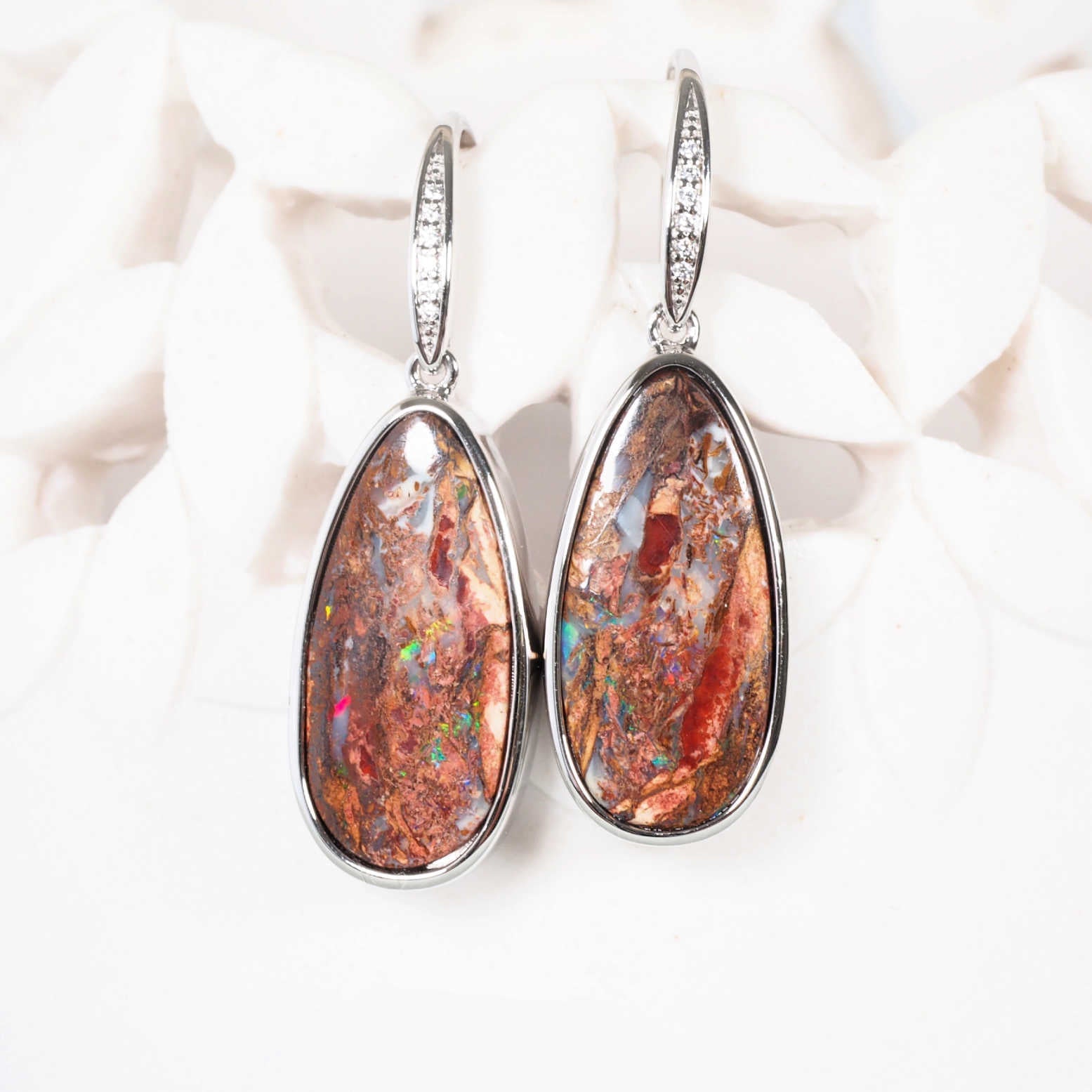 Close-up of a Queensland boulder opal earrings with vibrant flashes of colour in natural ironstone