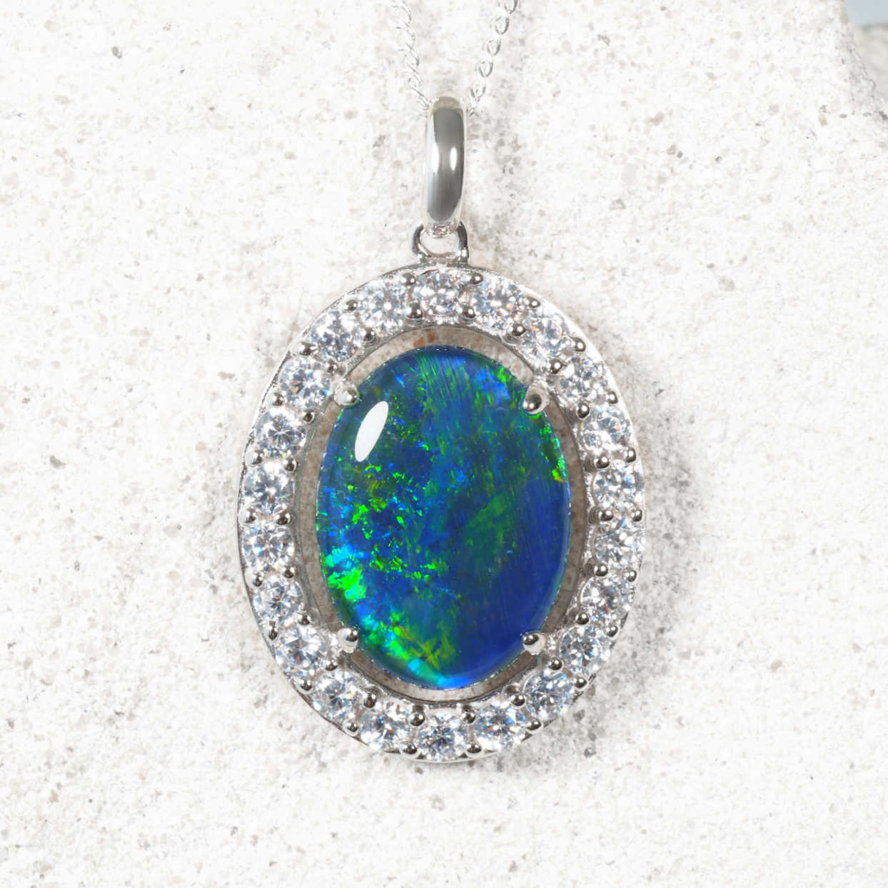 Halo-style silver opal necklace set with a blue-green Australian triplet opal and cubic zirconia border