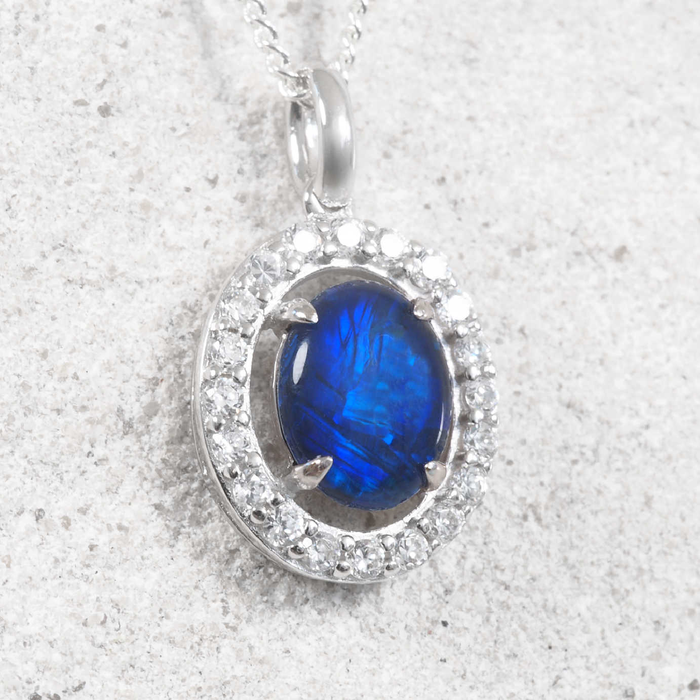 Oval Australian triplet opal pendant crafted in sterling silver, showcasing vivid blue and green natural play-of-colour with a sparkling cubic zirconia halo.