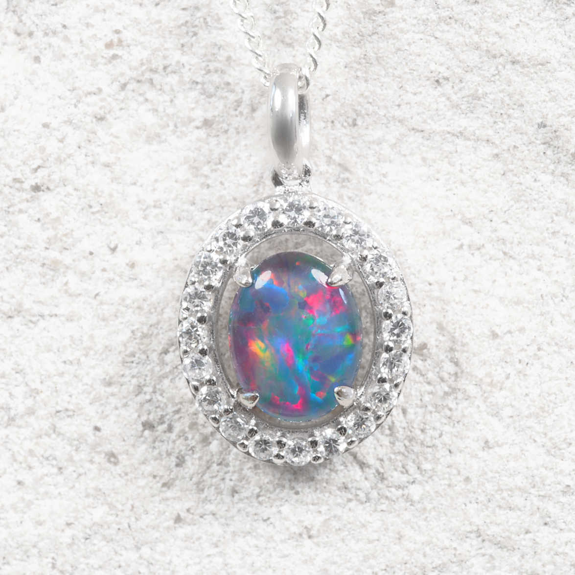 Oval Australian triplet opal pendant crafted in sterling silver, showcasing brilliant natural play-of-colour and framed by twenty sparkling cubic zirconias.