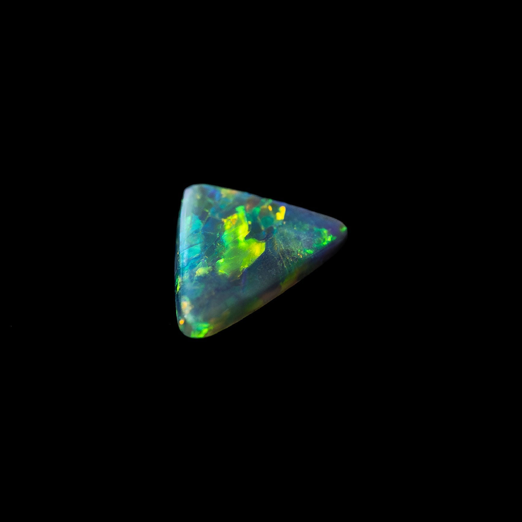 Triangular solid black opal stone with multicolor fluorescence