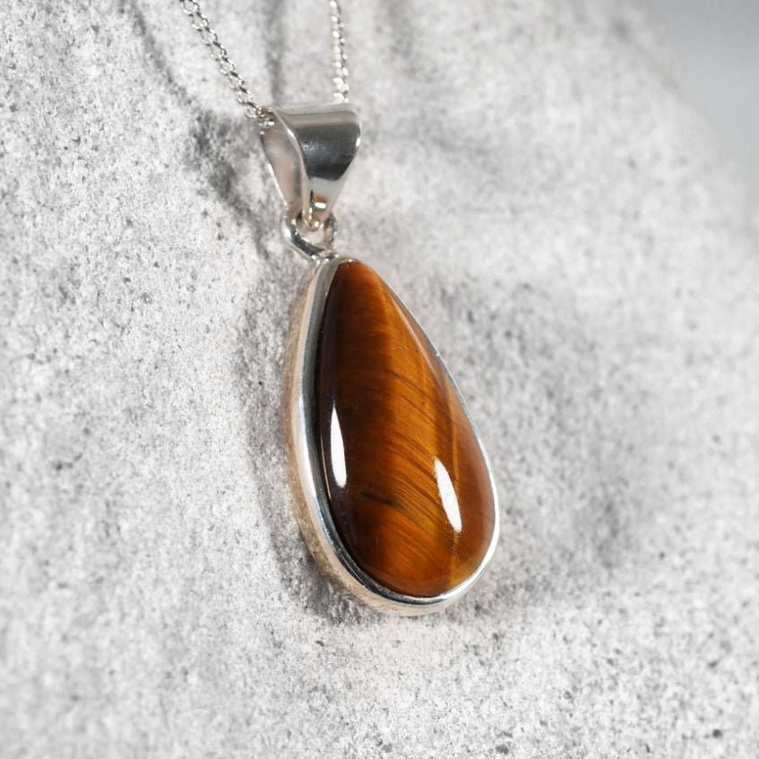 Teardrop-shaped tiger's eye pendant on a silver chain