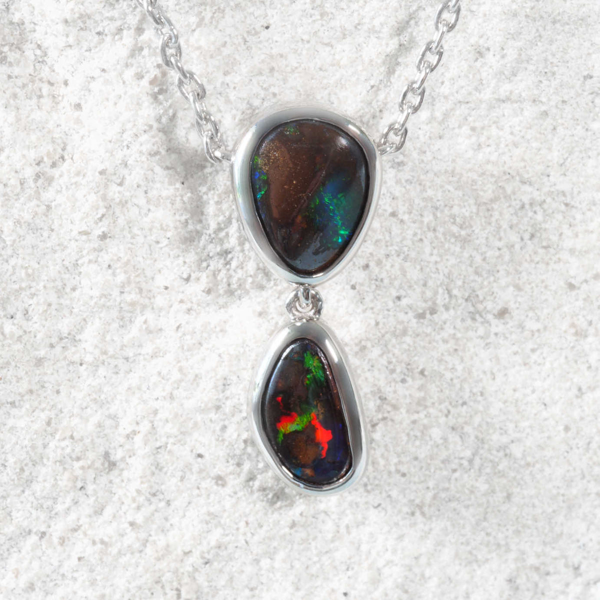 Boulder opal pendant necklace on a textured white background