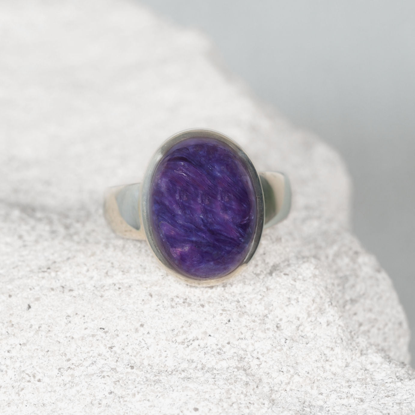 ‘Irene’ Charoite ring with a small round purple gemstone featuring soft lavender and white swirls, set in polished silver.