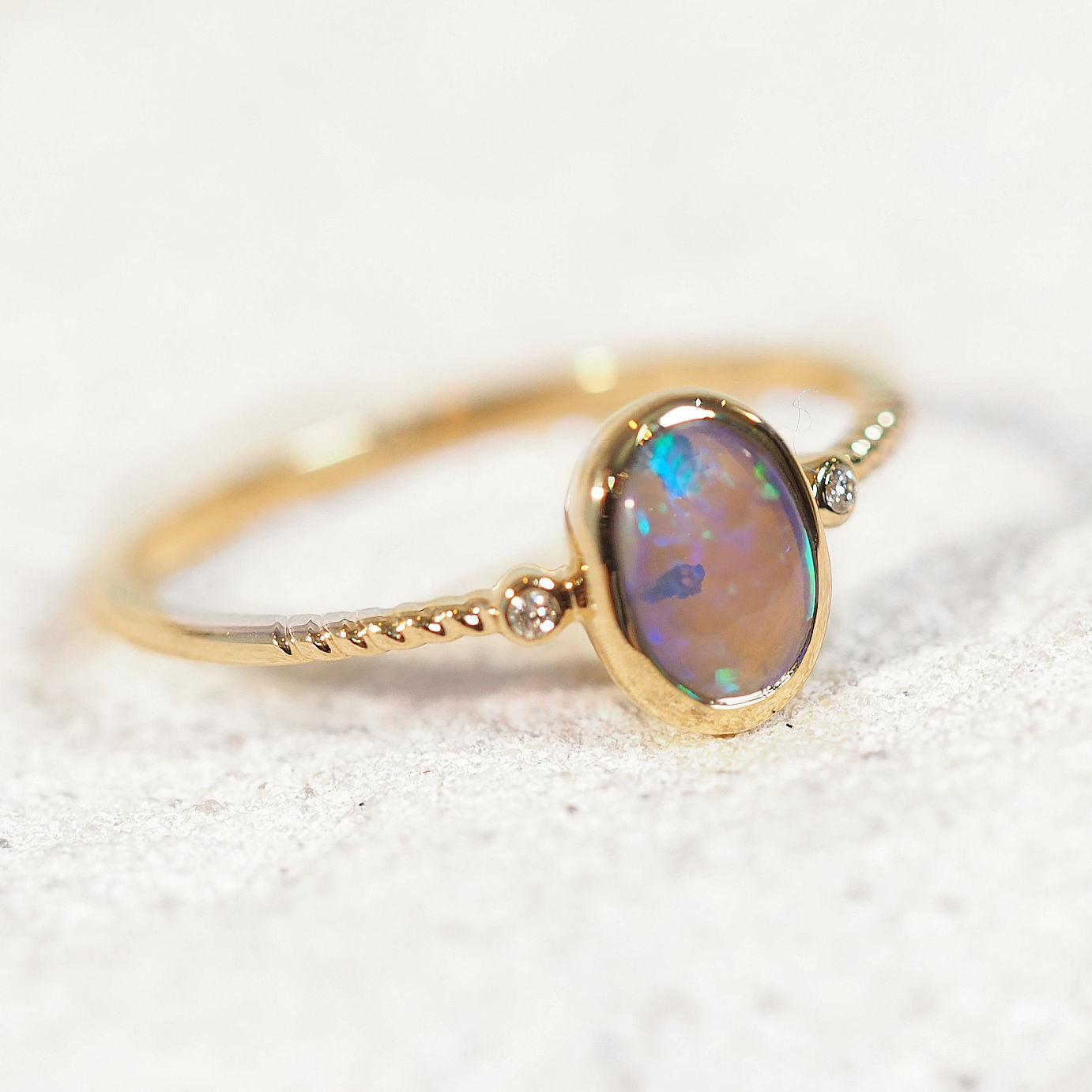 Gold ring with an black crystal opal stone on a white background