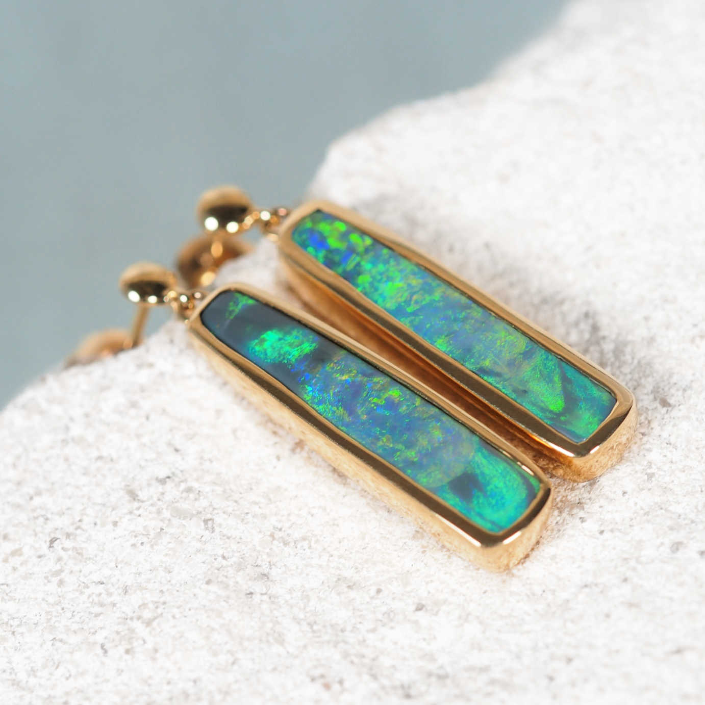 Pair of Australian Lightning Ridge black opal stud earrings in polished 14ct yellow gold, handcrafted by Black Star Opal.