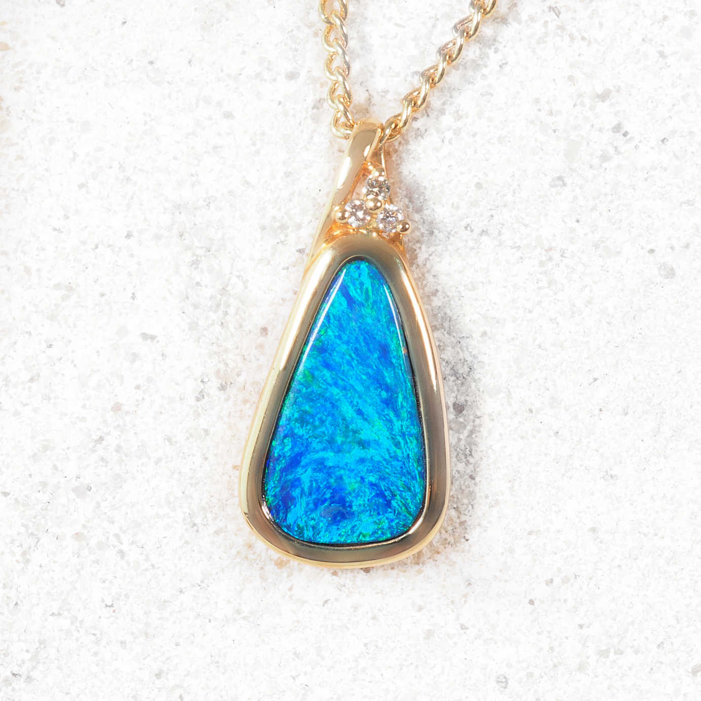 Teardrop opal pendant in 14ct yellow gold with three sparkling diamond accents.