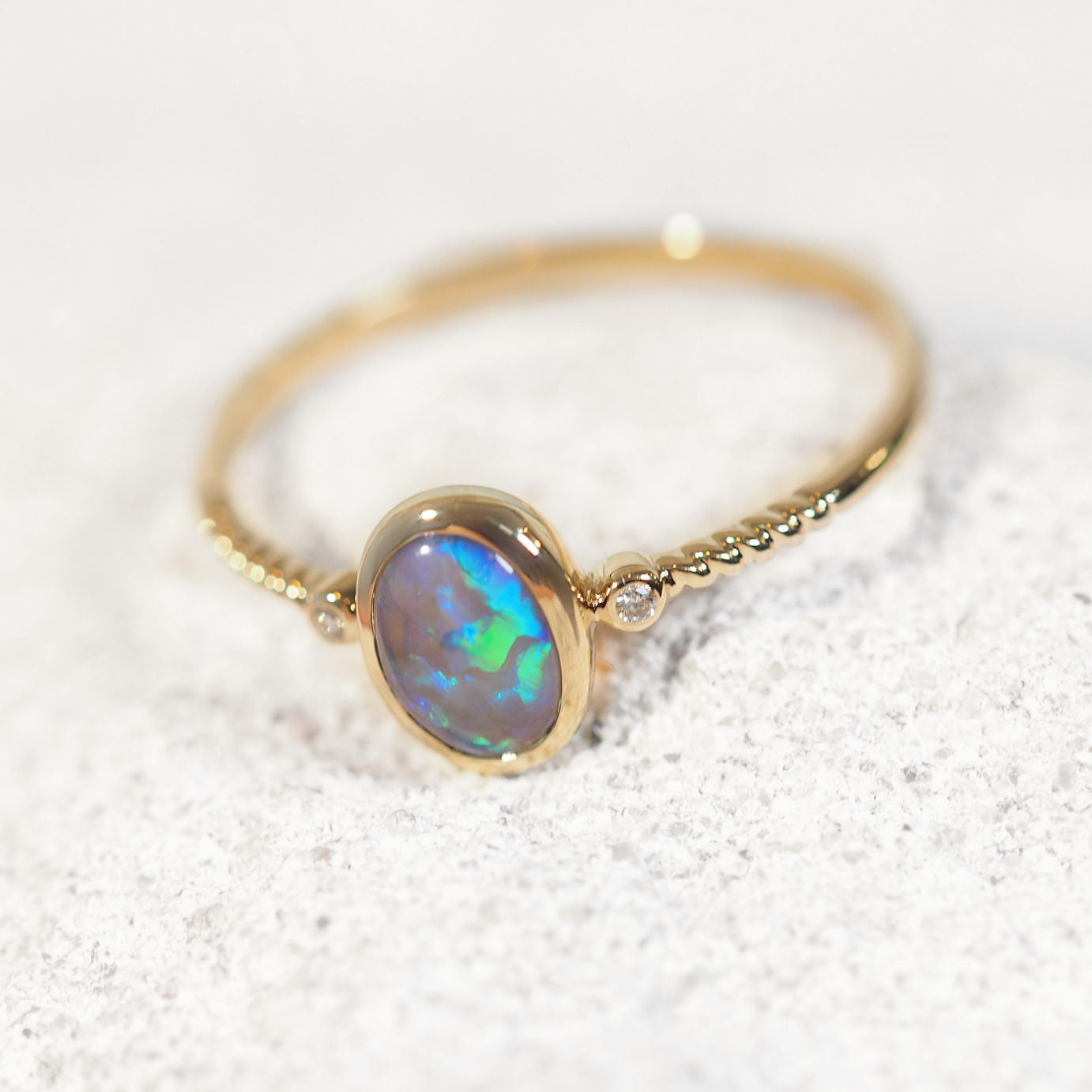 Gold ring with a black opal gemstone on a light background