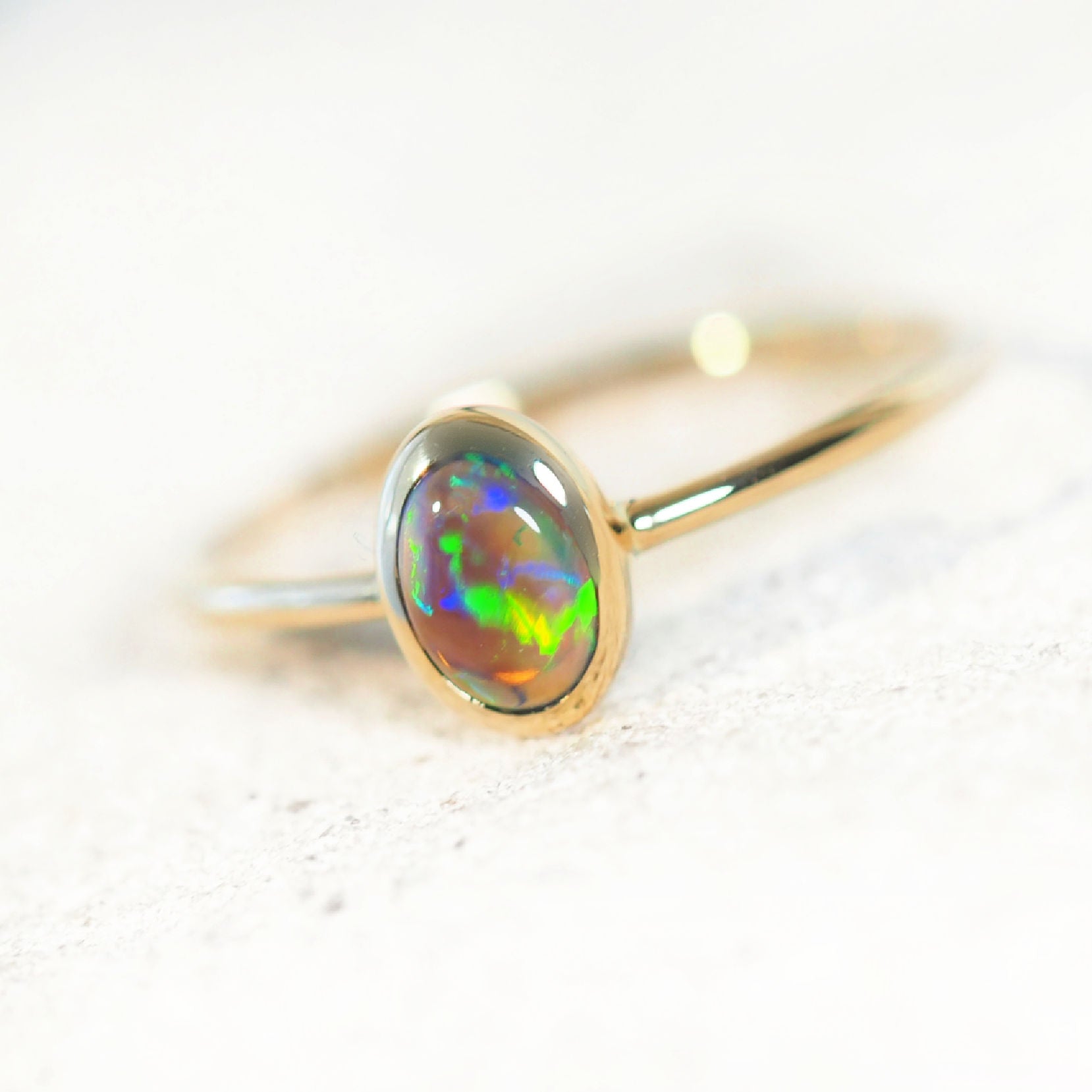 Gold ring with a colorful opal stone on a light background