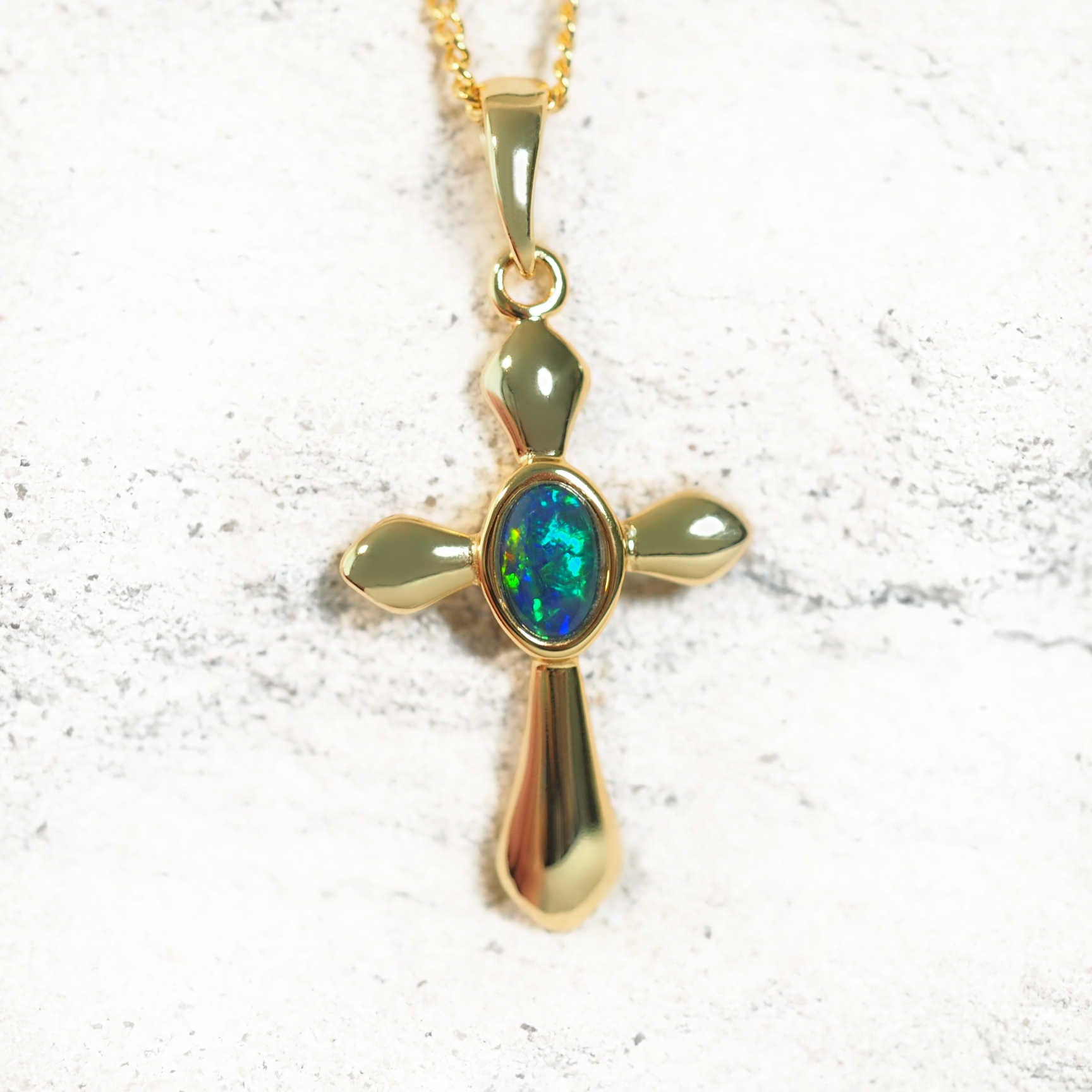 Gold-plated silver cross-shaped opal necklace with bezel-set blue and green Australian triplet opal, shown with matching chain.