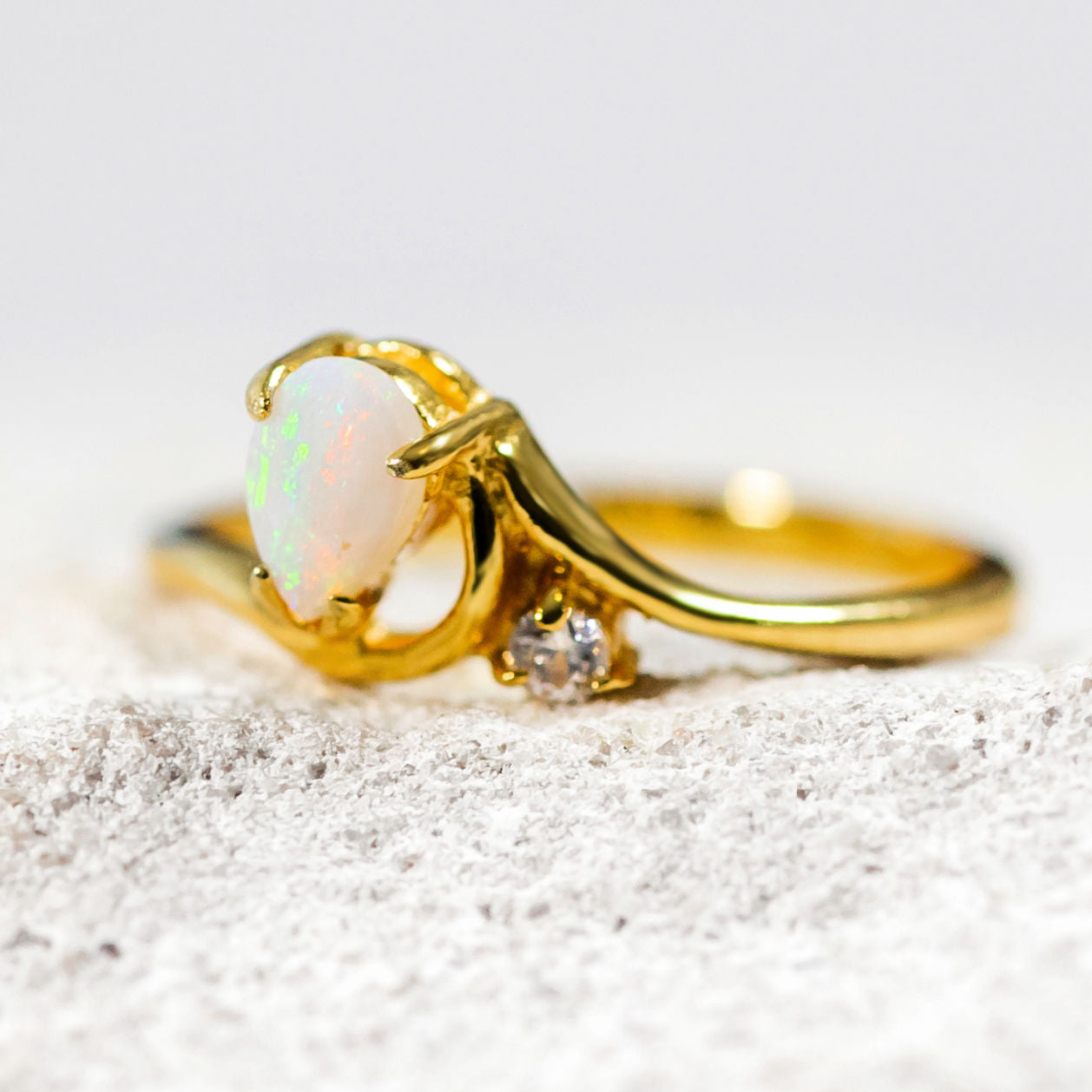 Elegant gold plated silver opal ring featuring teardrop solid opal with vibrant multi-coloured flashes and cubic zirconia