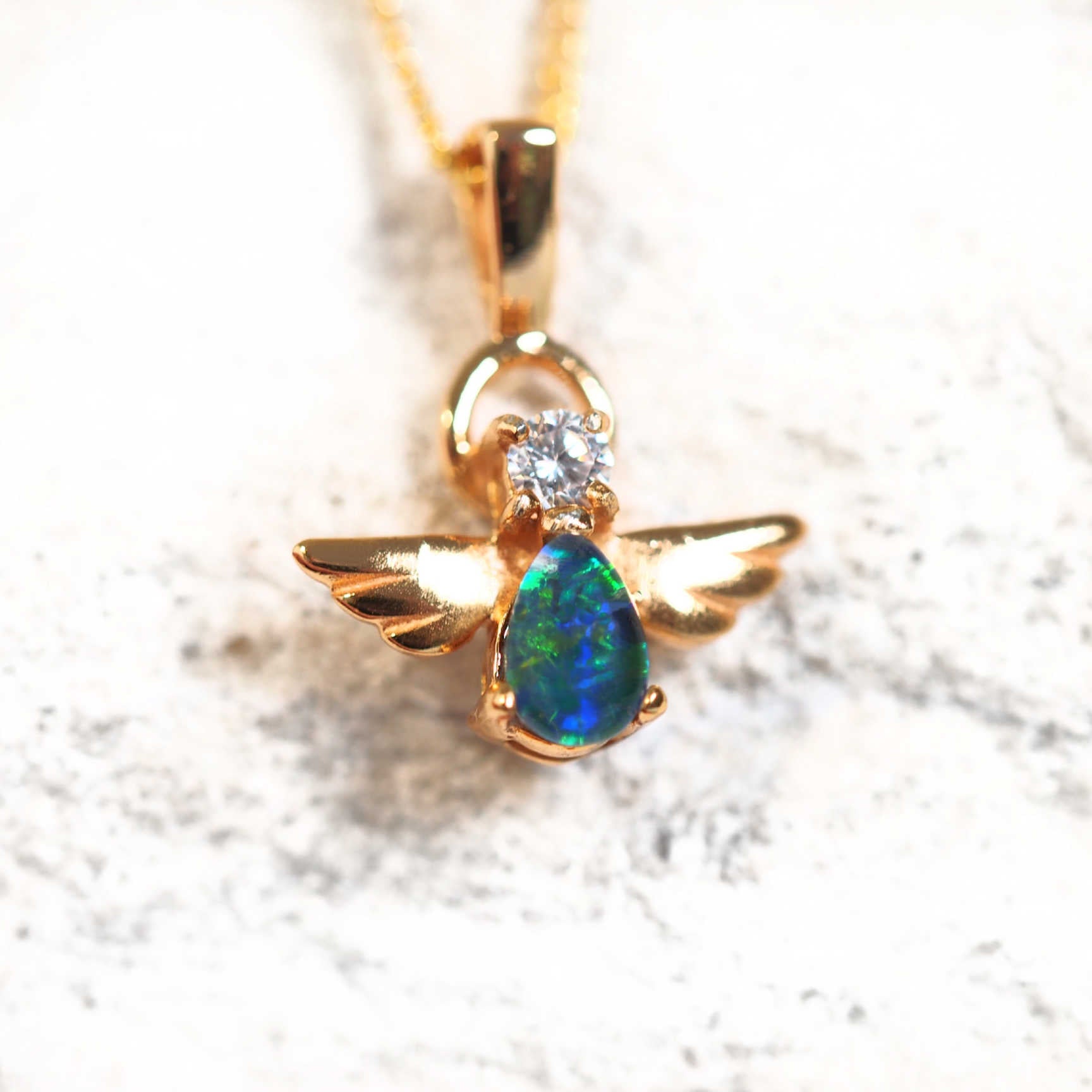 Gold-plated silver angel opal pendant with a blue and green teardrop-shaped opal and a sparkling cubic zirconia accent.