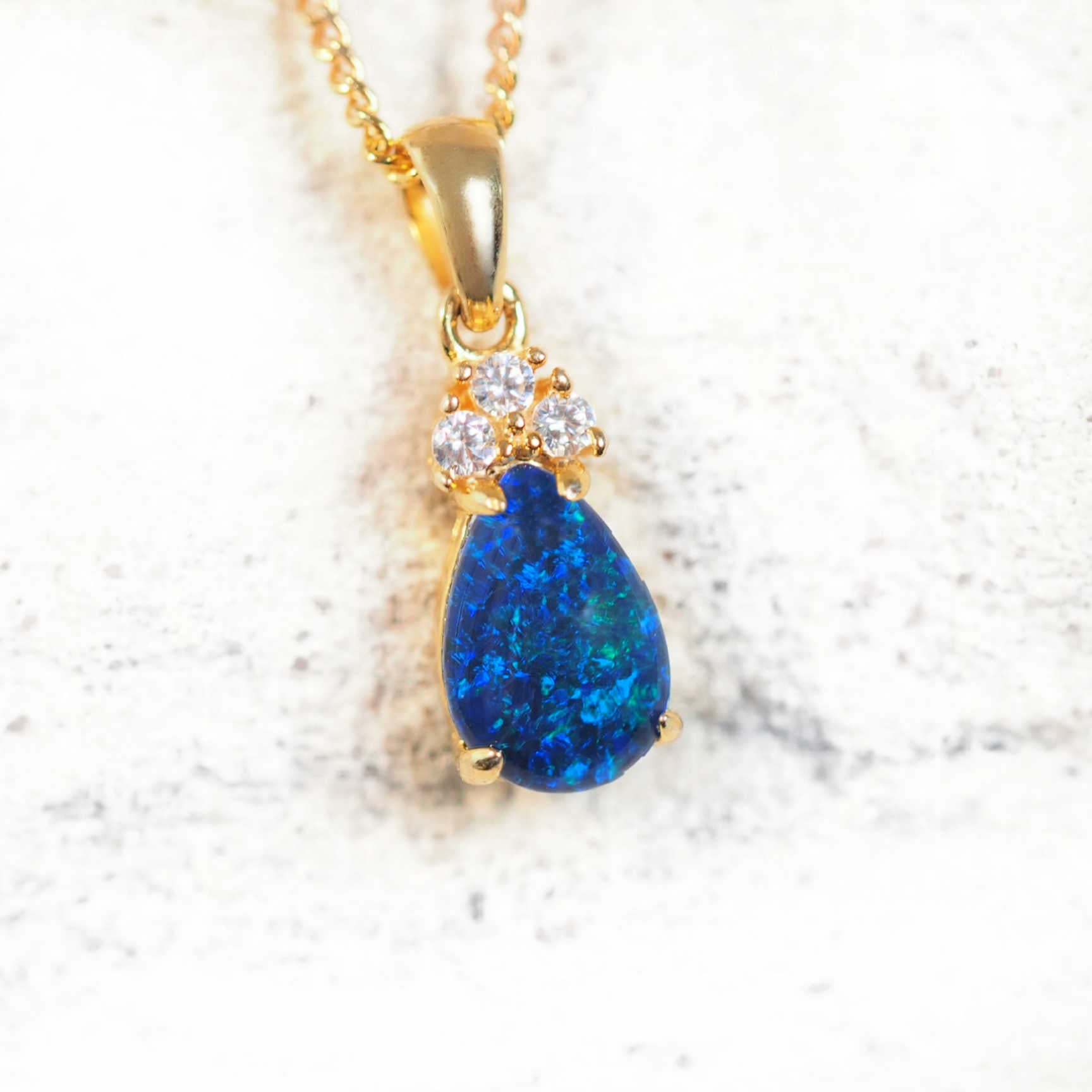 Gold-plated silver opal pendant with blue and green teardrop-shaped opal and trio of cubic zirconias