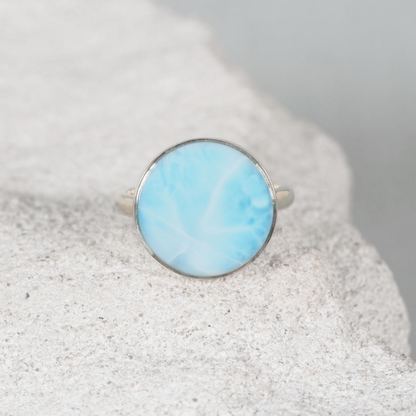 Larimar silver ring in a circle shape on a sandy background
