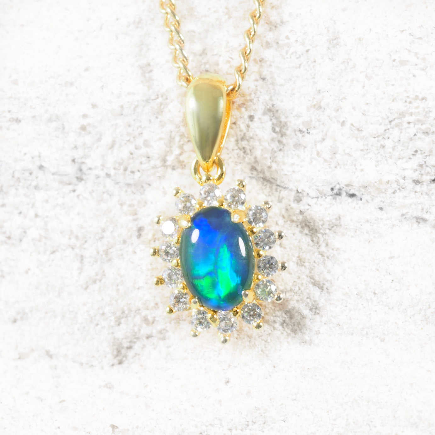The ‘Duchess Blue’ opal pendant in gold-plated silver showcases a blue and green Australian triplet opal with a halo of 14 cubic zirconias.
