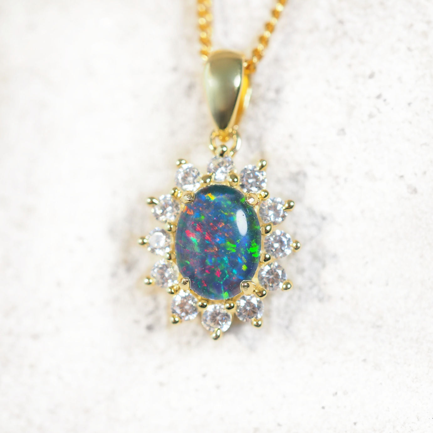 'Princess' opal pendant in polished gold-plated silver with claw-set oval Australian triplet opal and halo of 12 cubic zirconias