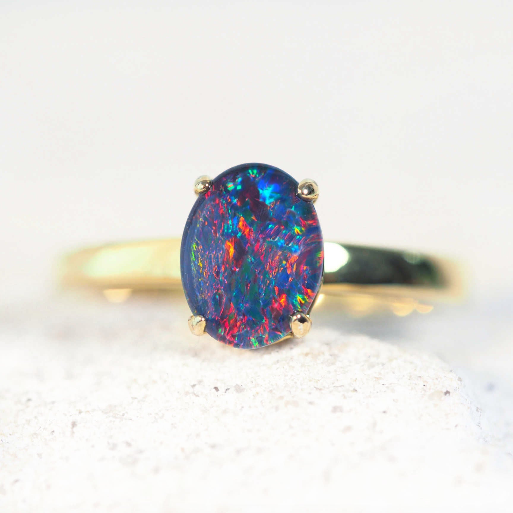 Gold ring with a colorful opal stone on a light background