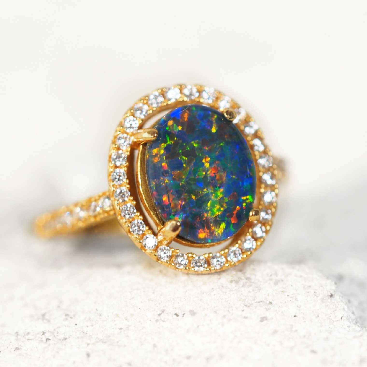 Gold ring with an opal stone and crystal accents on a white background