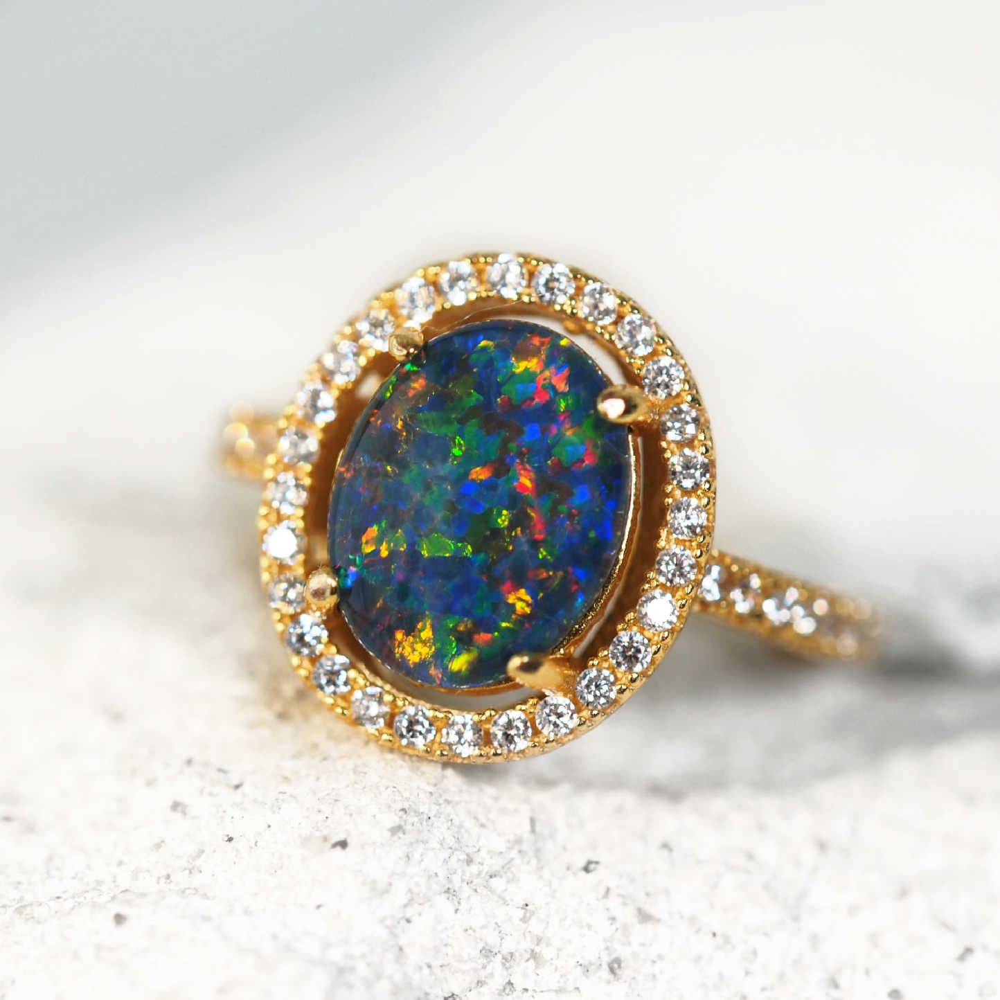 Ring with a colorful opal stone and diamond accents on a light background