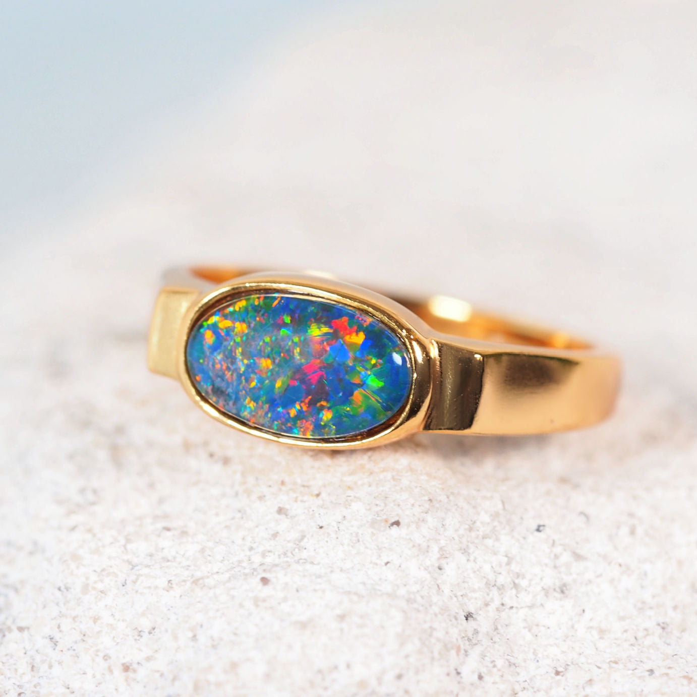Gold ring with a colorful opal stone on a white background