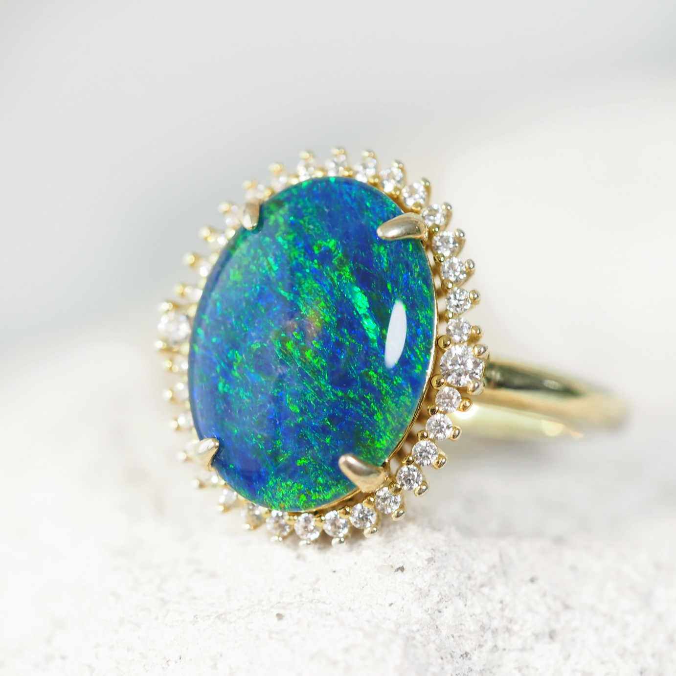 Ring with a blue and green opal stone and gold plated silver setting on a light background
