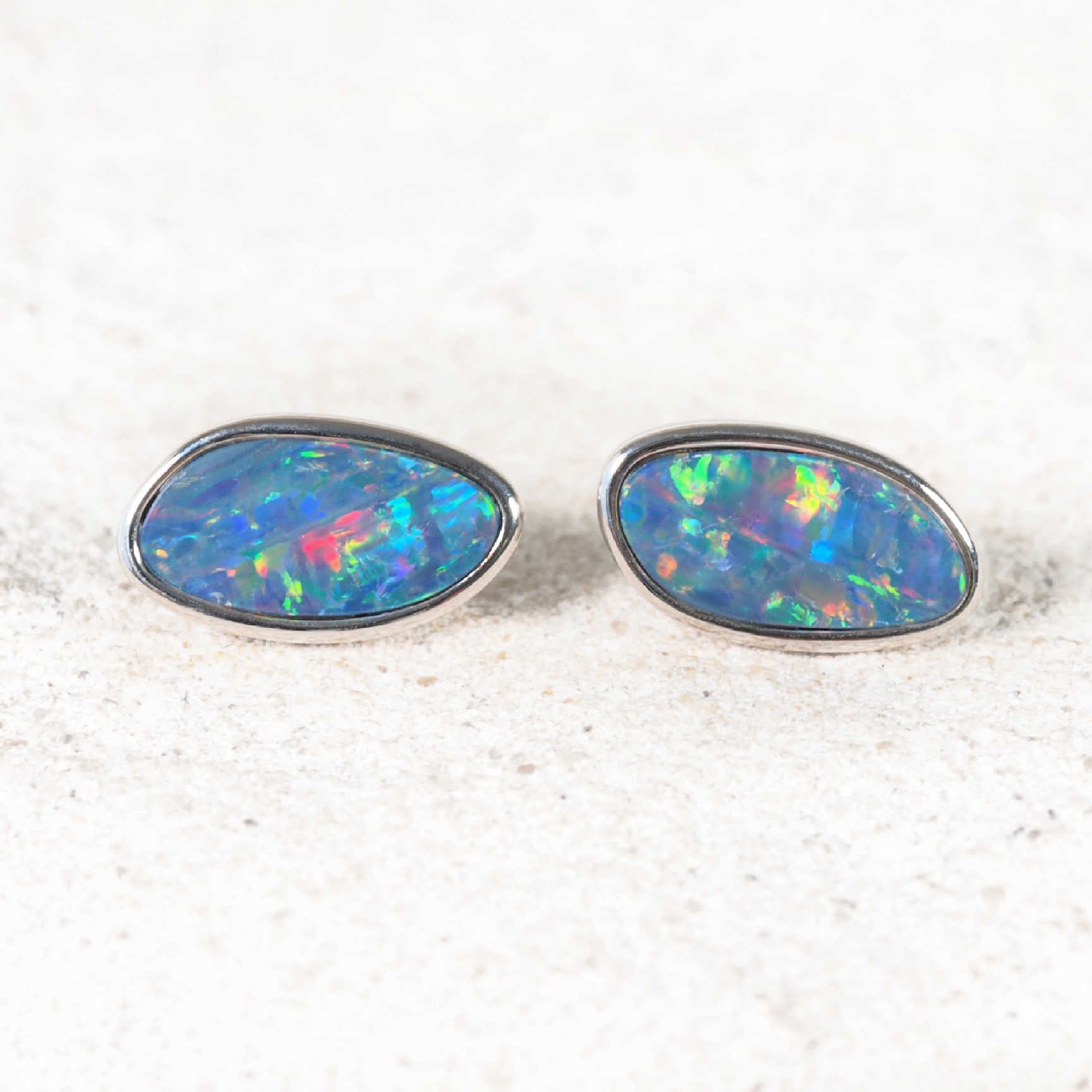 Doublet opal earrings set in sterling silver featuring freeform-shaped opals with vibrant blue, green, and gold flashes