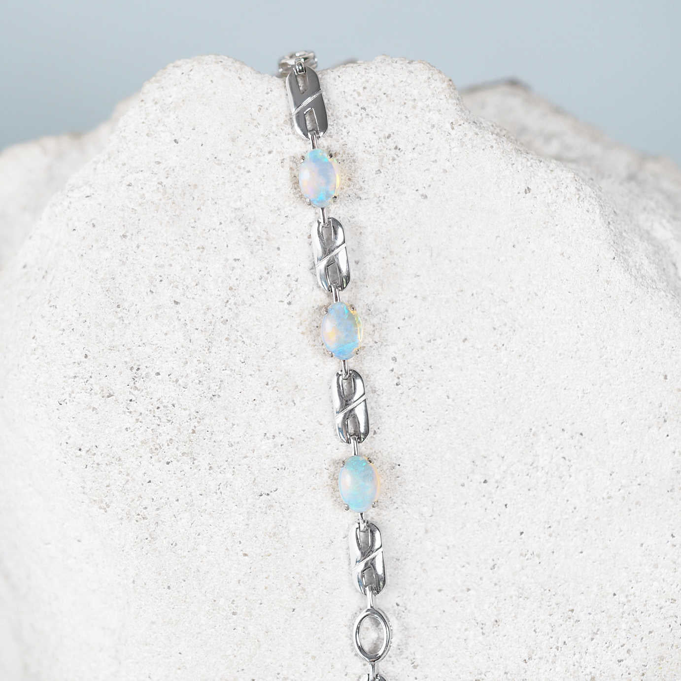 Silver bracelet with blue opal stones on a textured white surface
