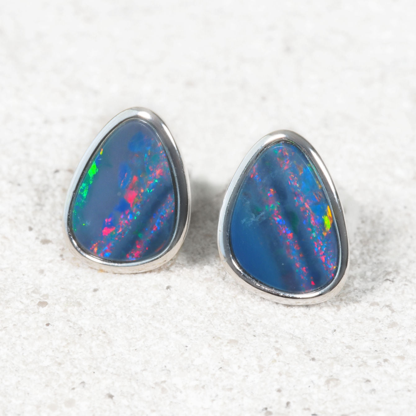 Opal earrings with silver setting on a textured white background