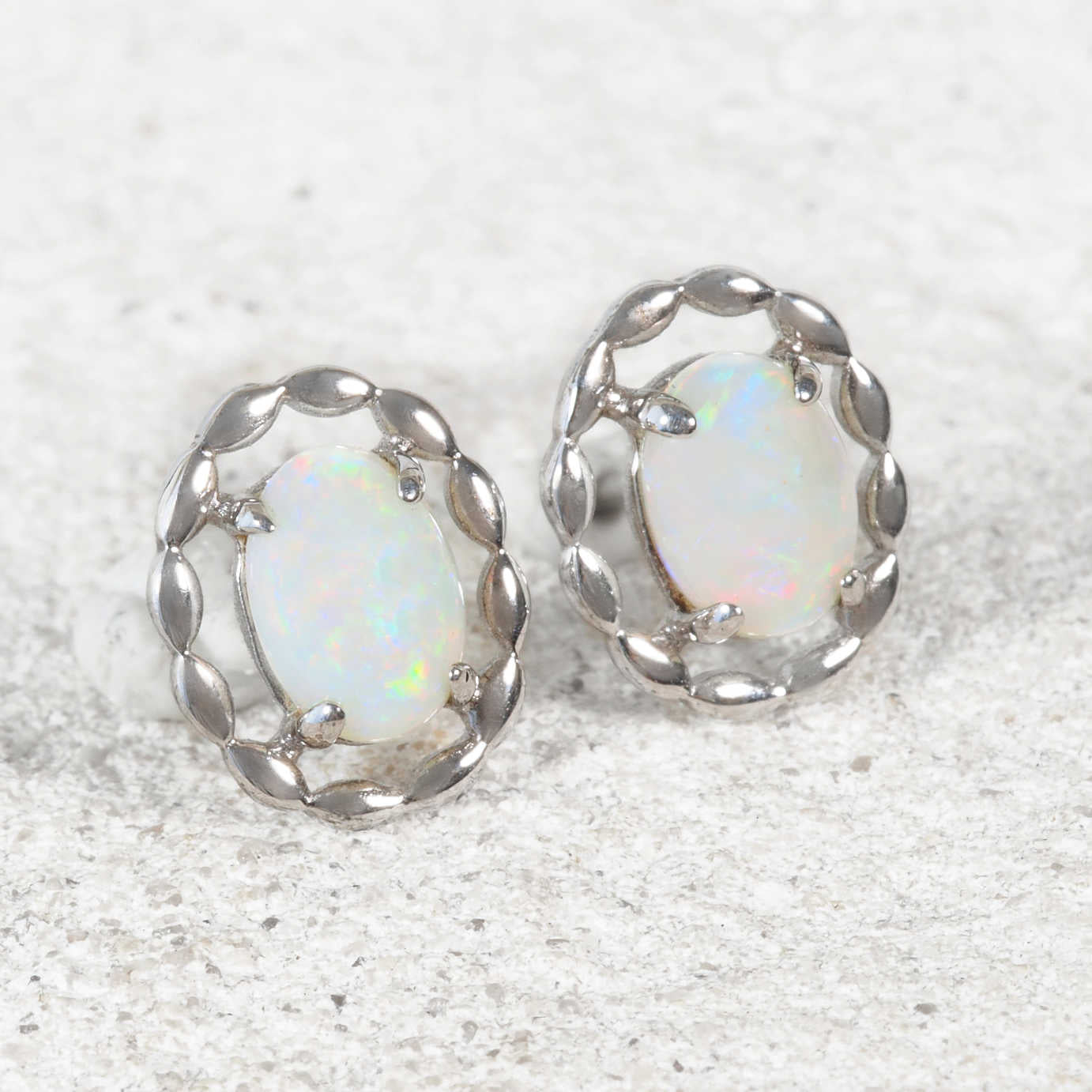 Close-up of ‘Harley’ opal earrings showcasing vibrant play-of-colour in sterling silver claw-set design.