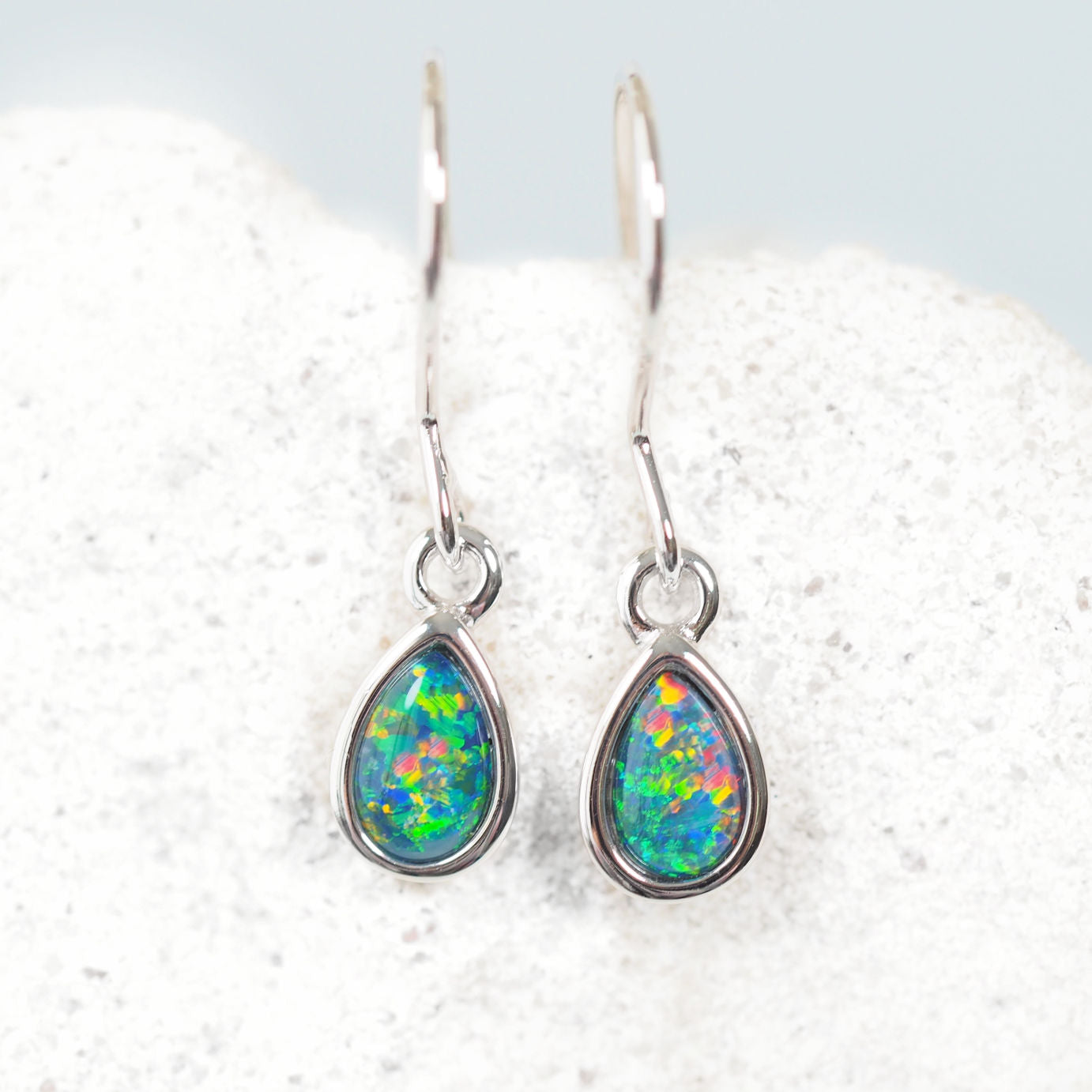 Teardrop-shaped opal earrings on a white background