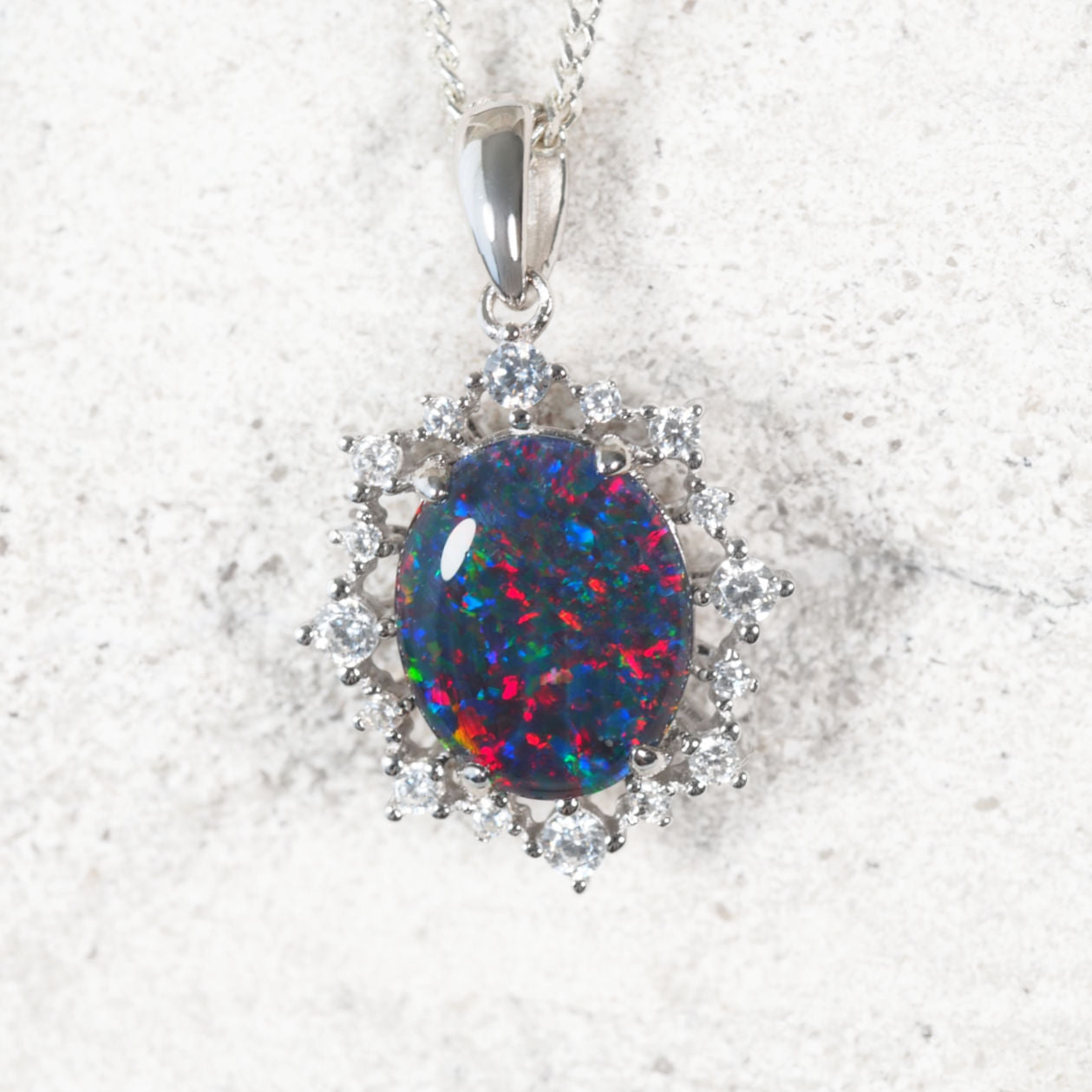 ‘Victoria’ sterling silver opal pendant with claw-set oval Australian triplet opal in vibrant multi-colour tones and halo of 16 sparkling cubic zirconias