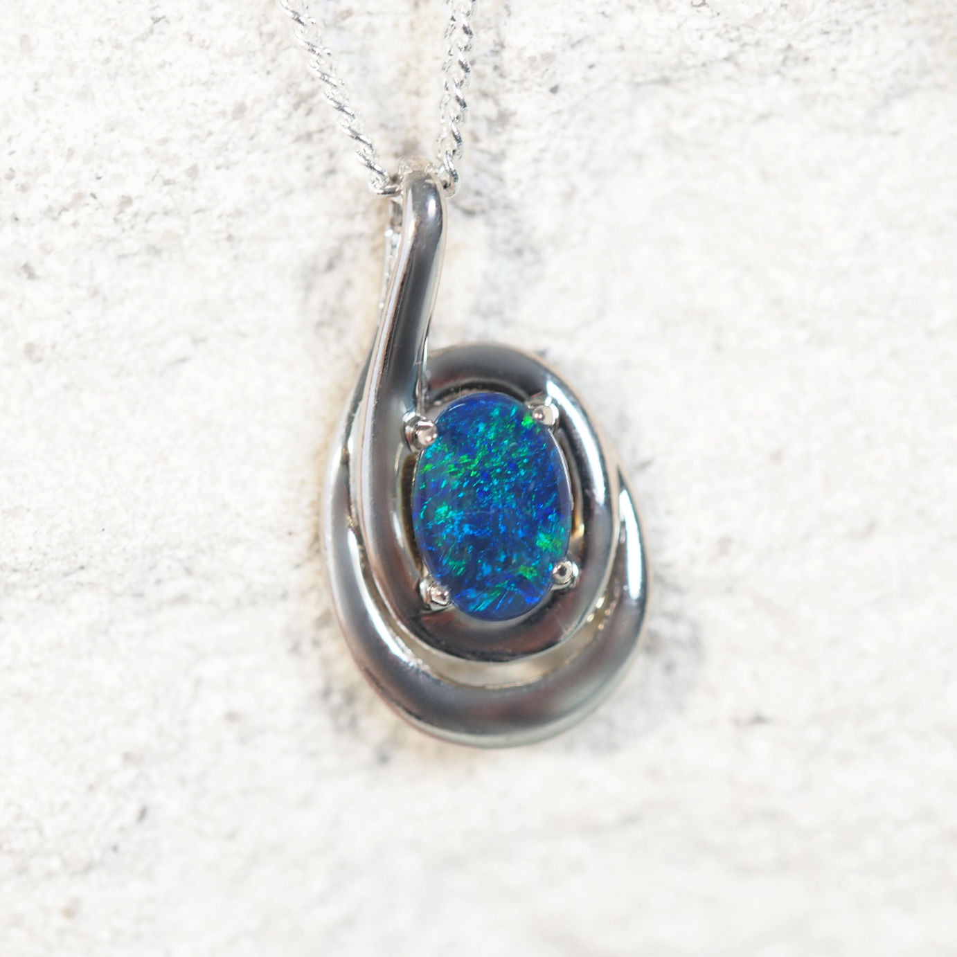 'Vianna Blue' opal pendant in sterling silver with double swirl design and claw-set oval Australian triplet opal in vivid blue and green tones