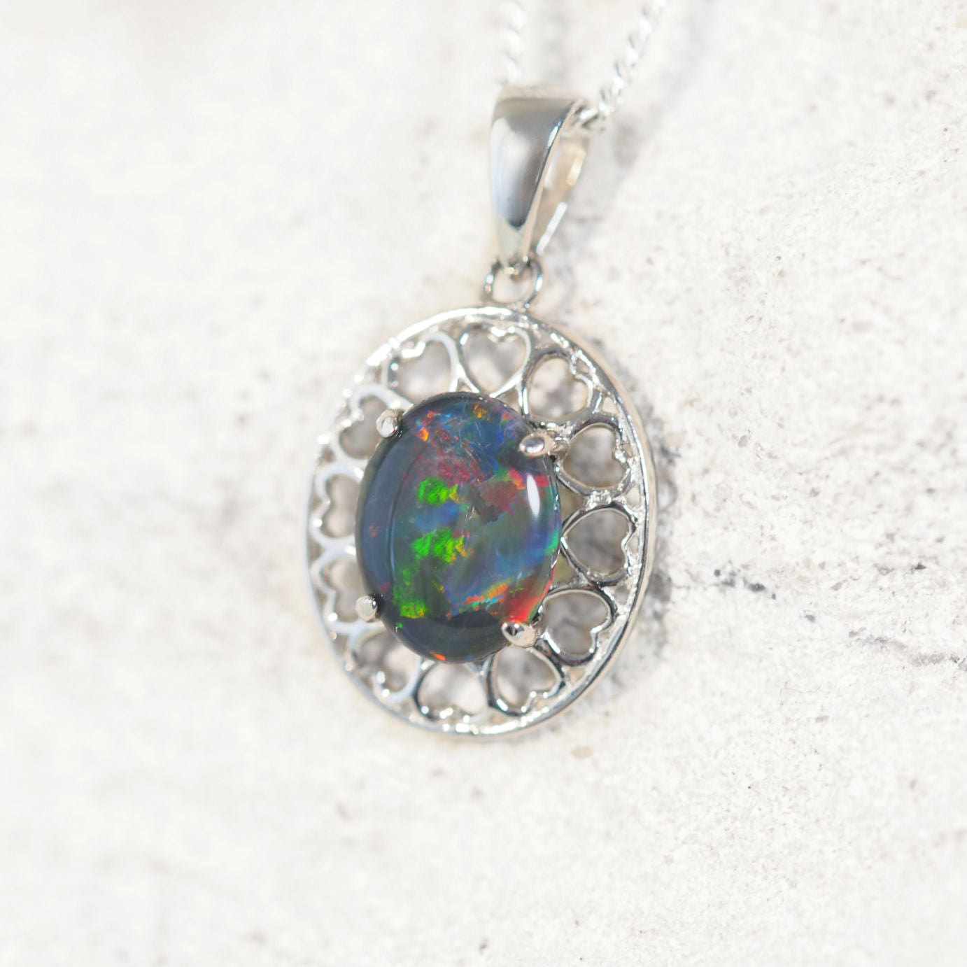 'Amore' opal pendant in sterling silver with decorative heart-pattern design and claw-set oval Australian triplet opal in vibrant multi-coloured tones