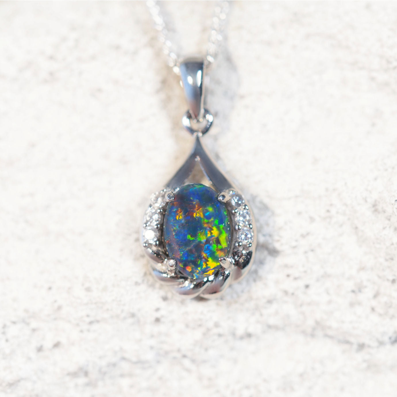 'Laina' opal pendant in sterling silver with claw-set oval Australian triplet opal in vibrant multi-coloured tones framed by six sparkling cubic zirconias