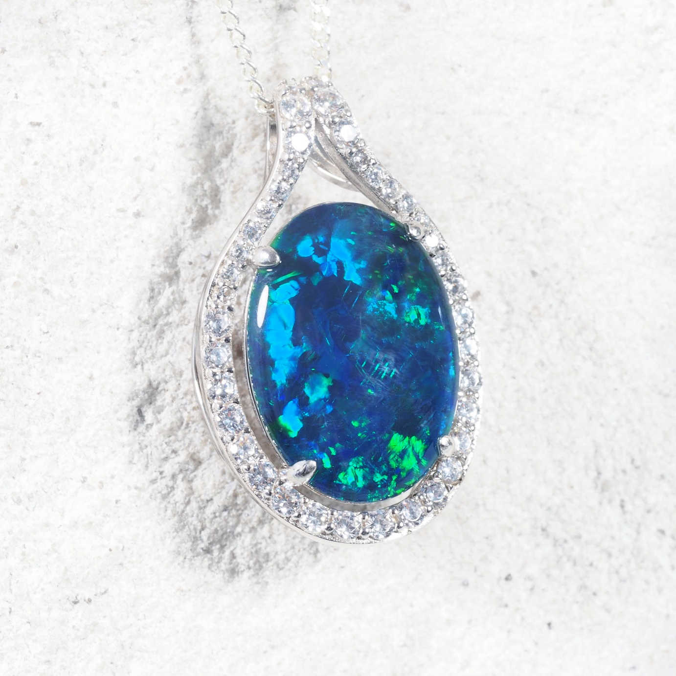 Statement 'Dianna Blue' opal necklace in sterling silver featuring claw-set oval Australian triplet opal in vivid blue and green tones with diamanté halo