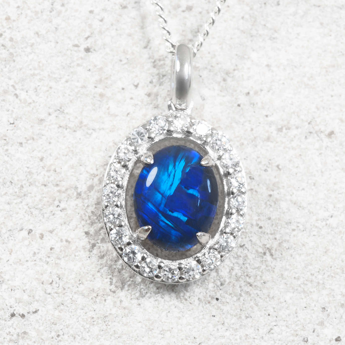 Sterling silver Australian triplet opal pendant featuring an oval blue and green opal surrounded by a halo of twenty sparkling cubic zirconias.