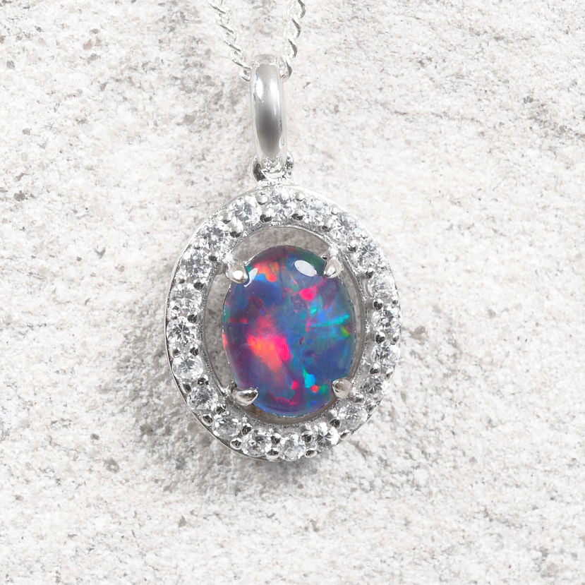 Sterling silver Australian triplet opal pendant featuring an oval genuine opal with vibrant blue, green, red and golden play-of-colour, surrounded by a halo of sparkling cubic zirconias.