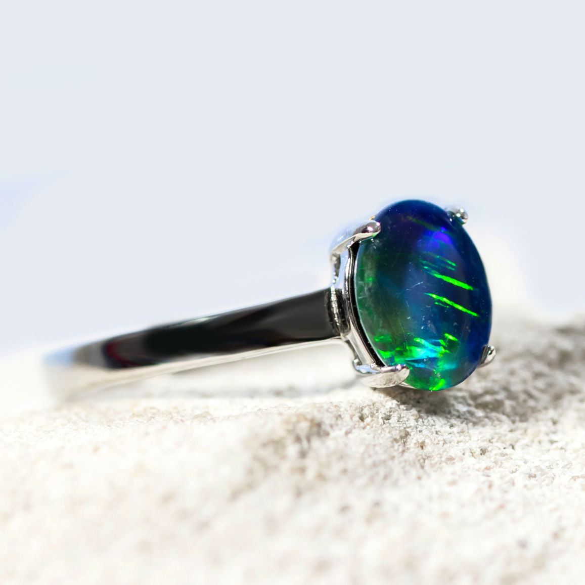 Ring with a green and blue opal gemstone on a light background