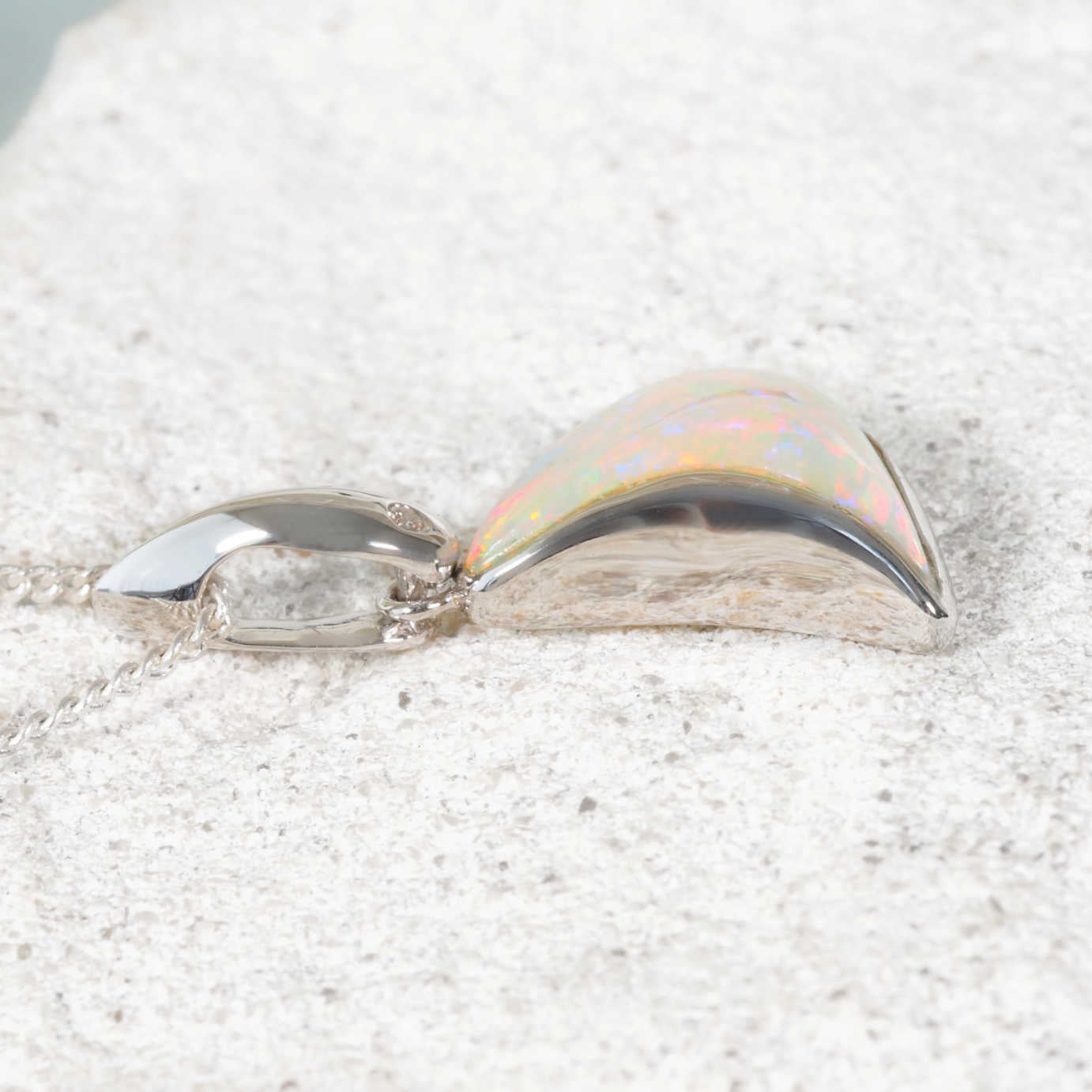 White gold opal pendant featuring a curved Coober Pedy solid opal with multi-coloured flashes and a diamond accent