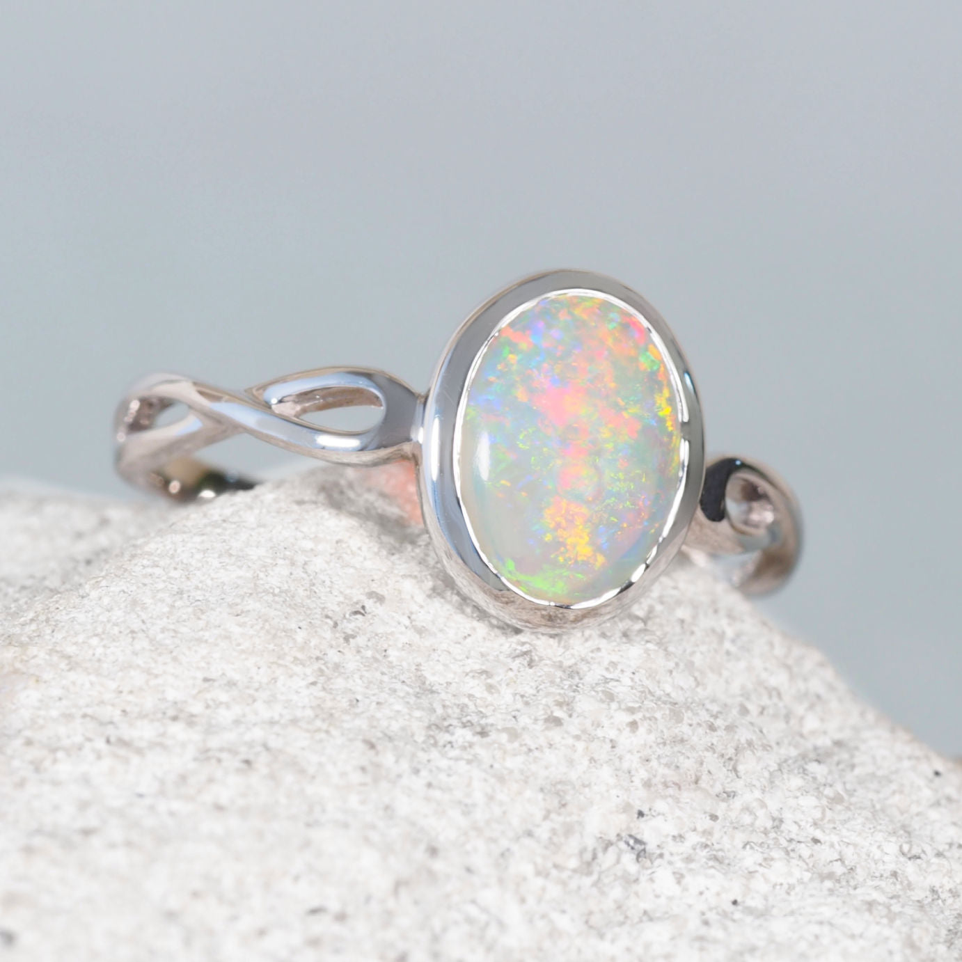 White gold opal ring with an opal stone on a textured surface