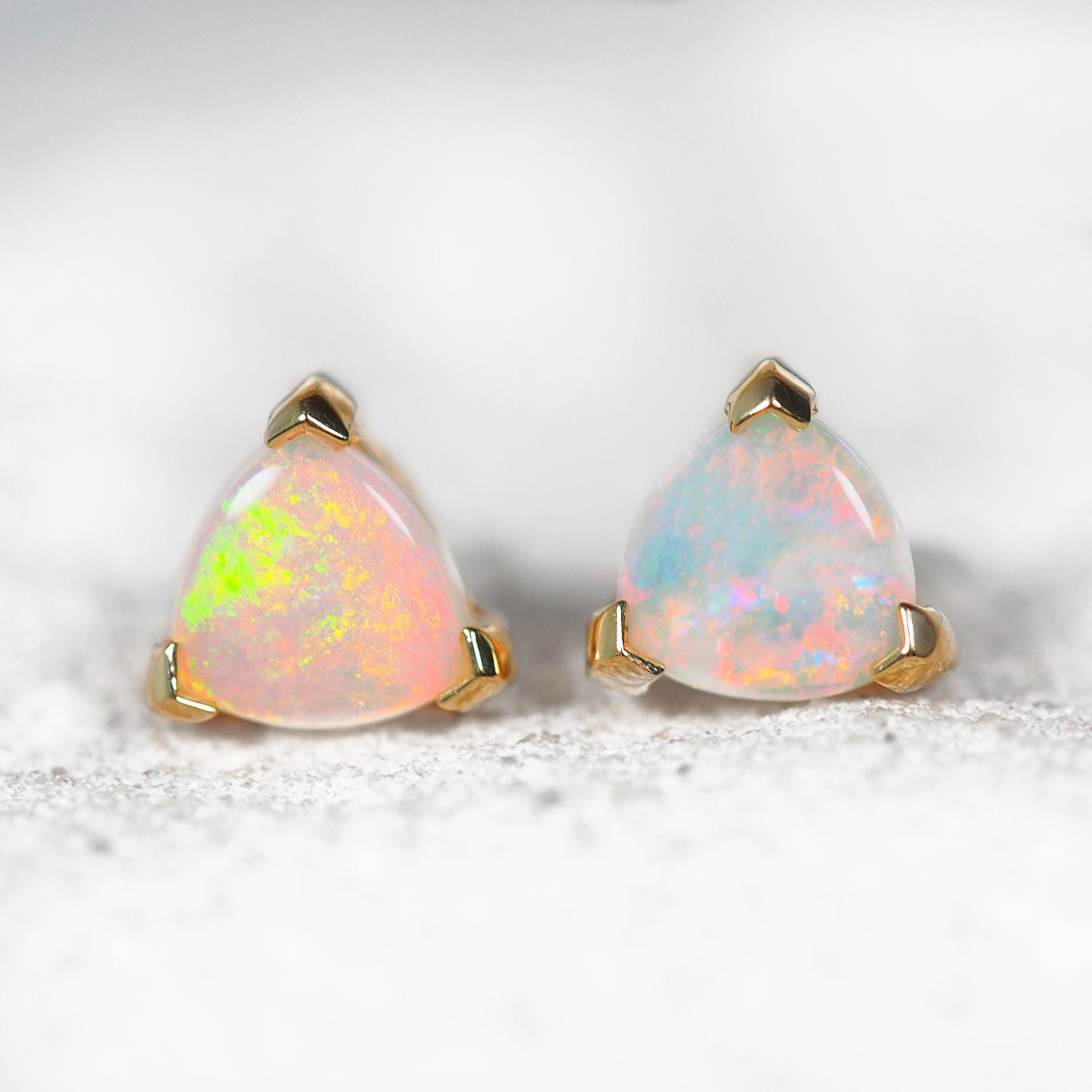 Pair of opal earrings with gold settings on a light background