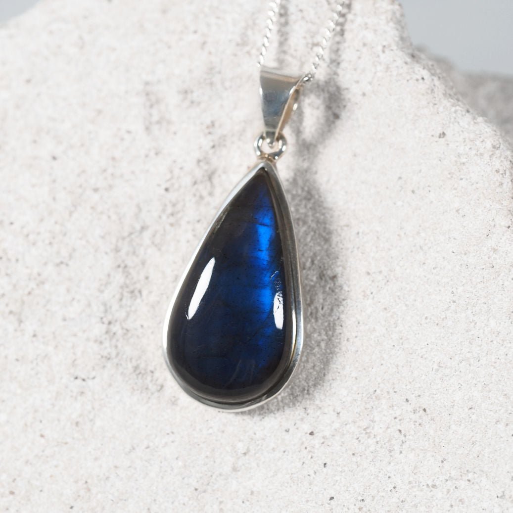 Teardrop-shaped blue pendant on a white background
