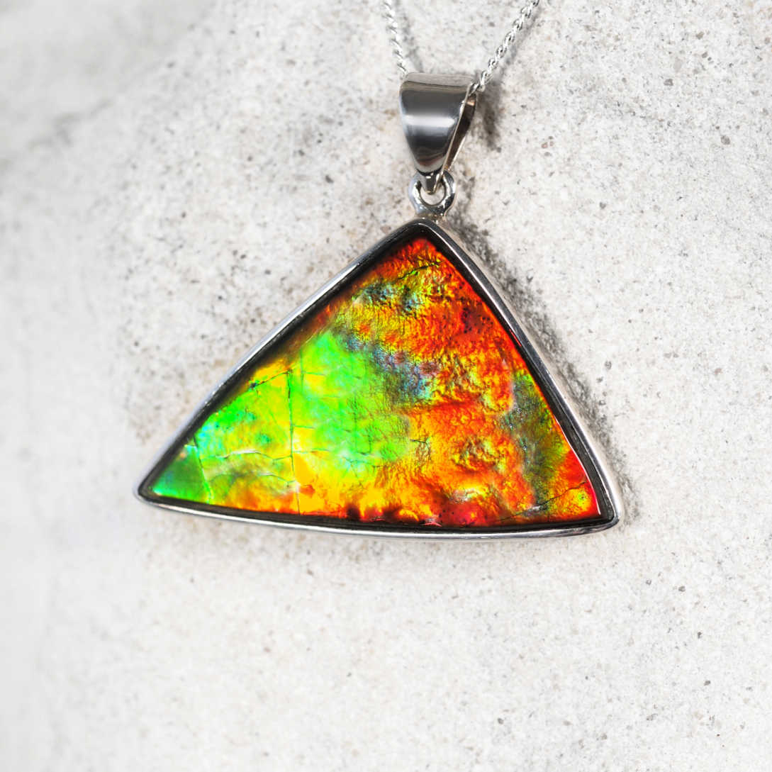 'Althea' Ammolite pendant in a triangular silver setting showcasing vibrant iridescent colors.
