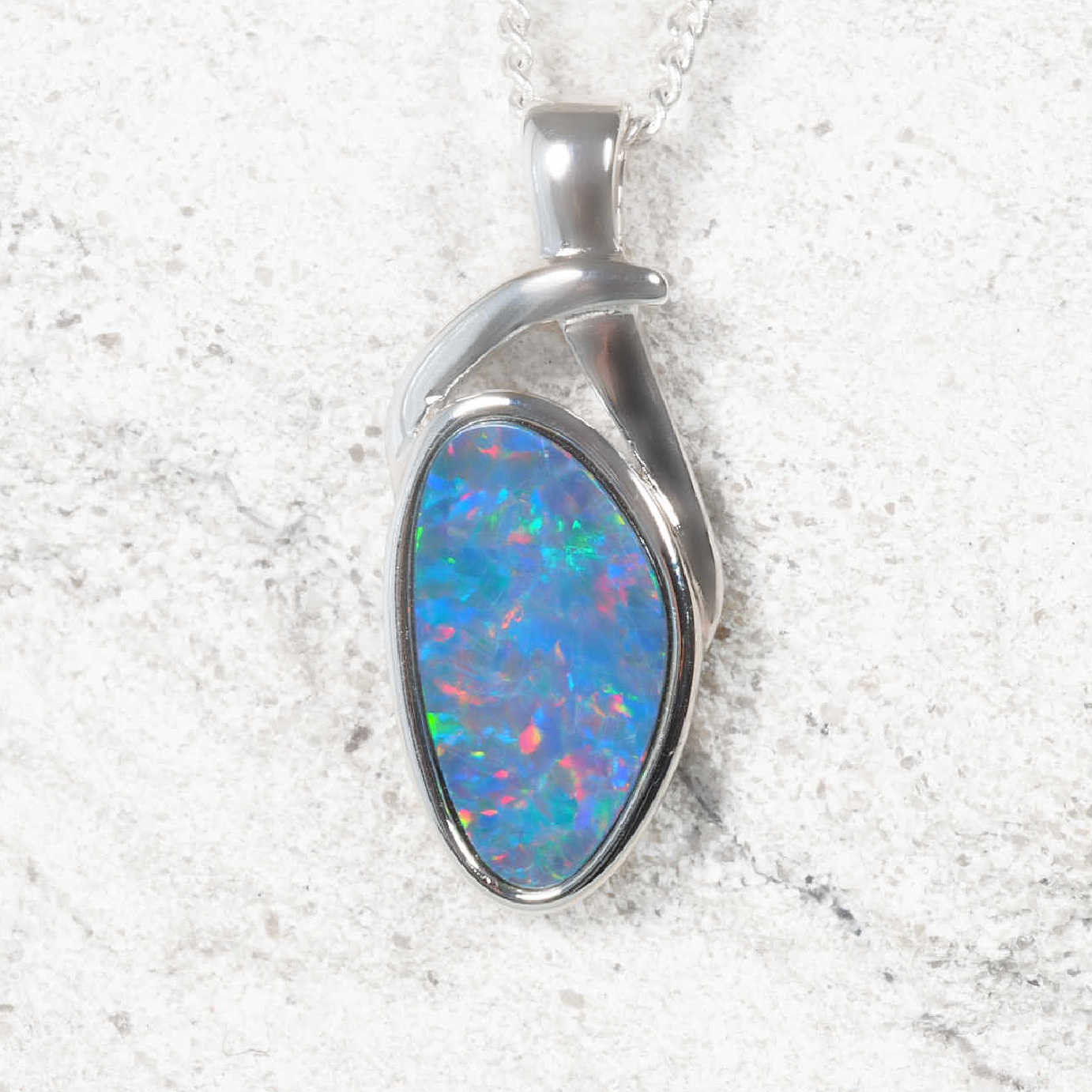 Opal pendant with silver setting on a textured white background